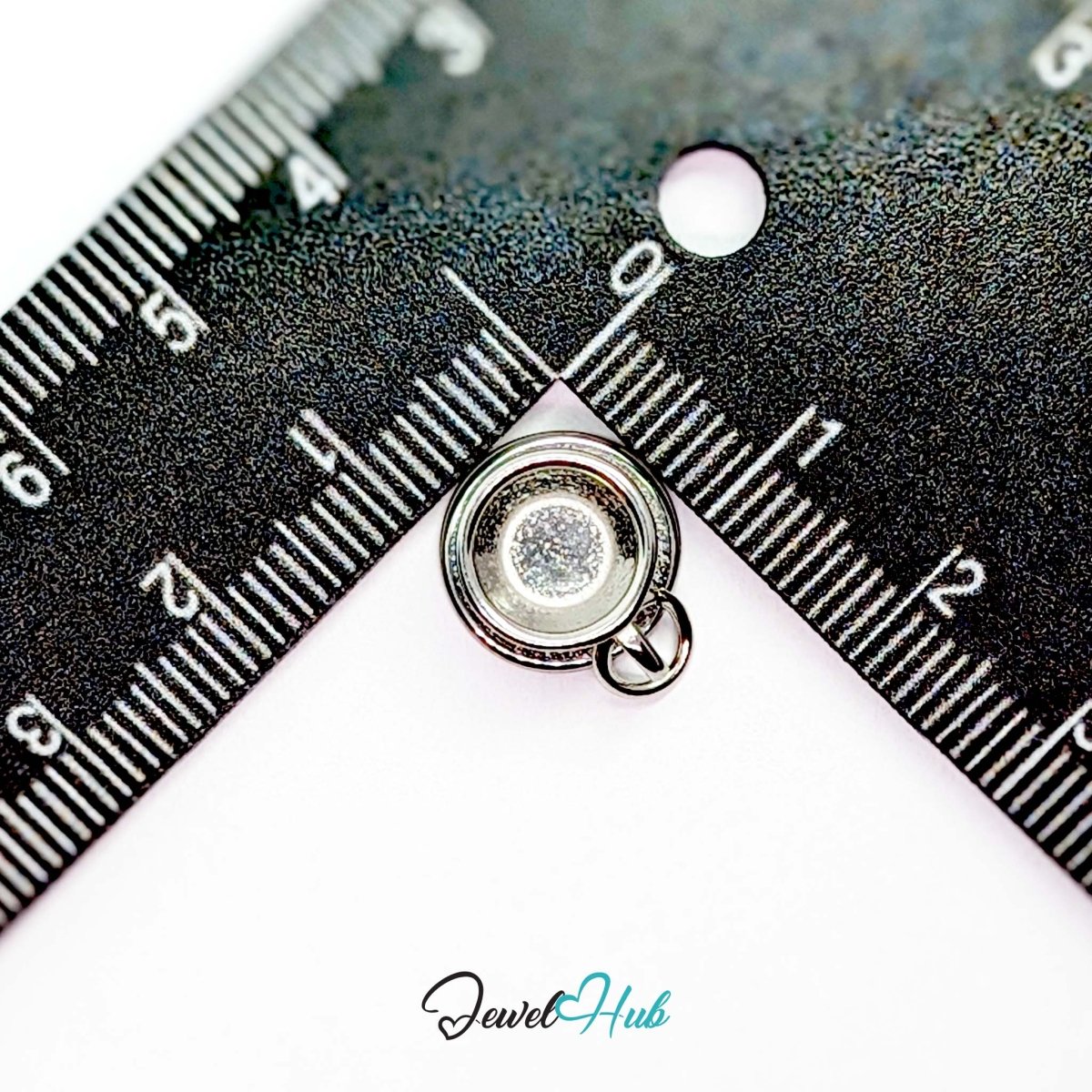 Three-dimensional coffee cup and saucer charm in silver stainless steel - beside a ruler for scale - JewelHub