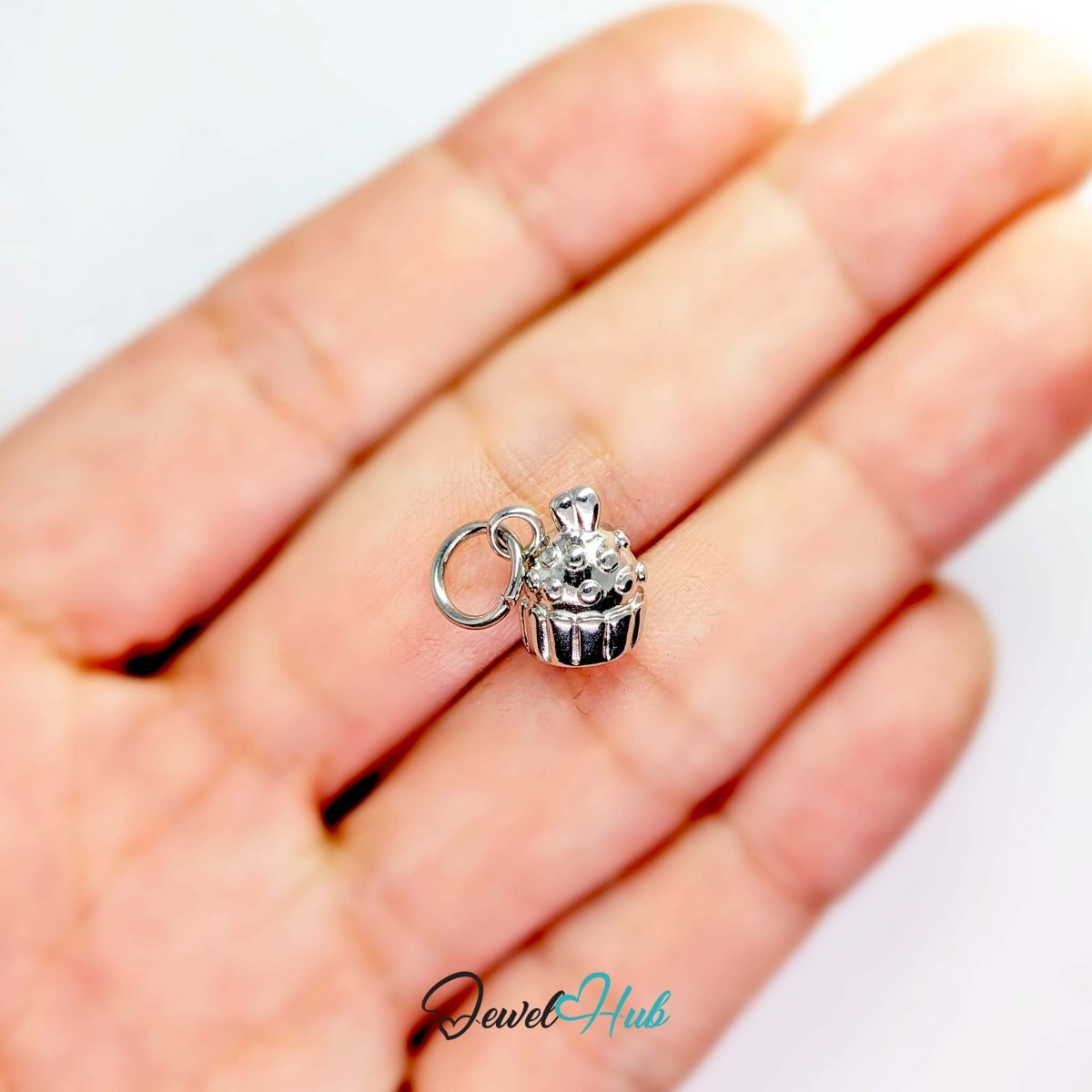 Three-dimensional cupcake charm in silver stainless steel - held in the hand for scale - JewelHub
