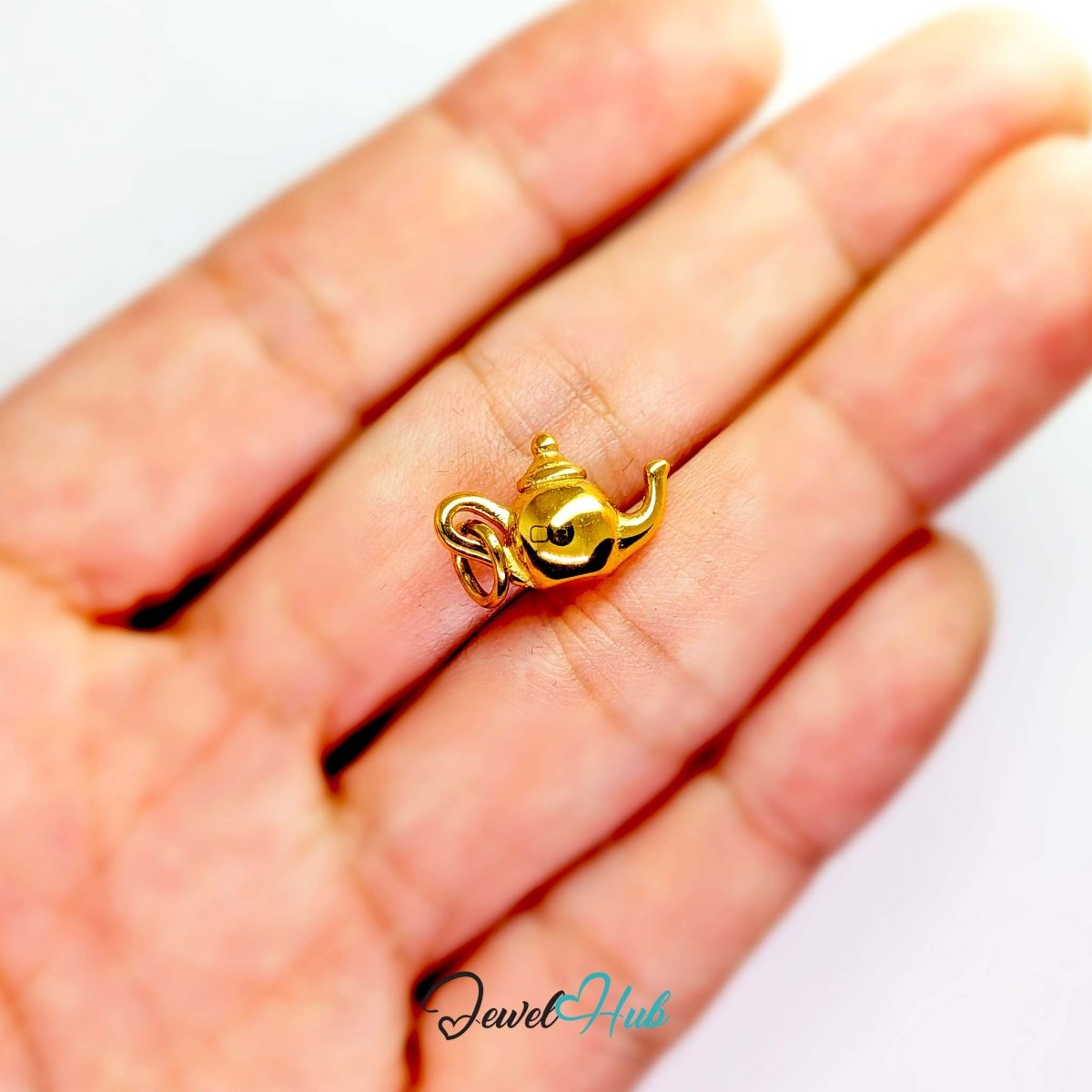Three-dimensional teapot charm in gold stainless steel - held in the hand for scale - JewelHub