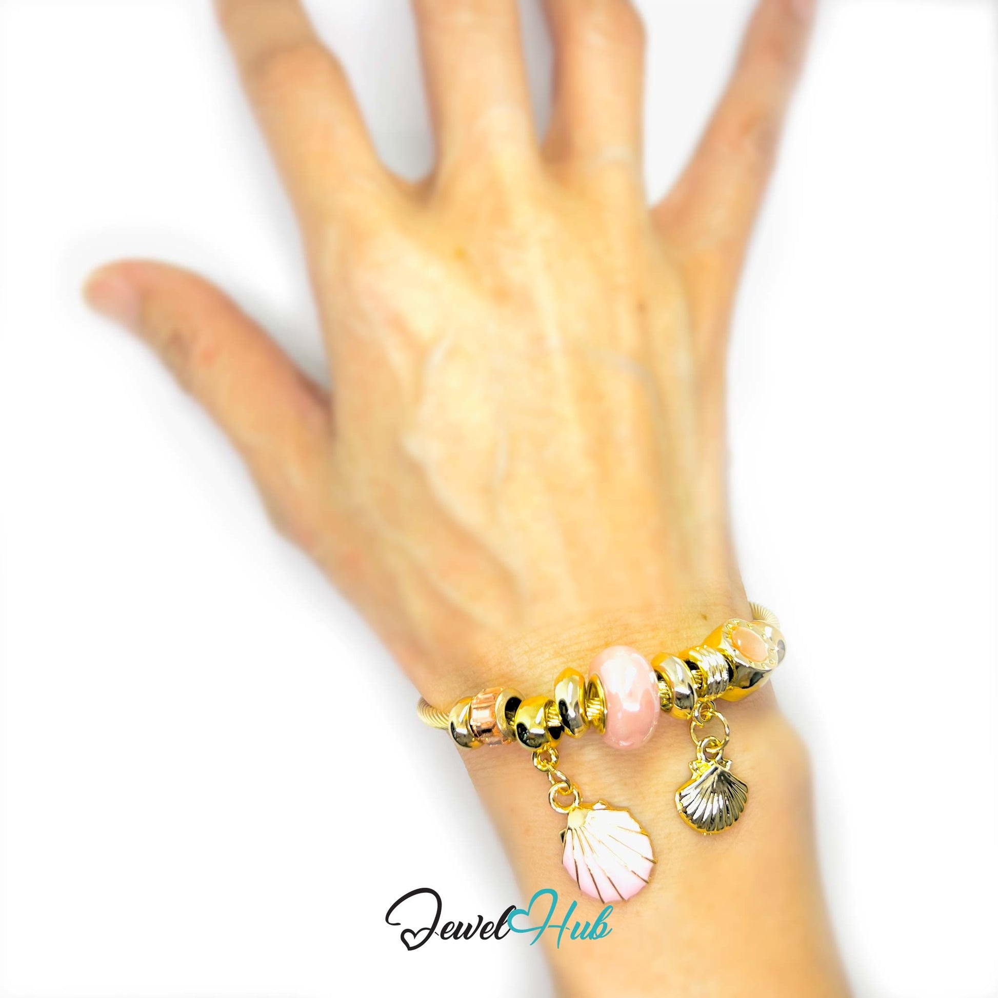 Hand wearing a gold bracelet with shell charms on a white background, branded 'Jewel Hub'.