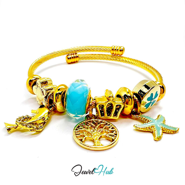 Gold bracelet with various charms including a blue heart, starfish, and tree of life on a white background.