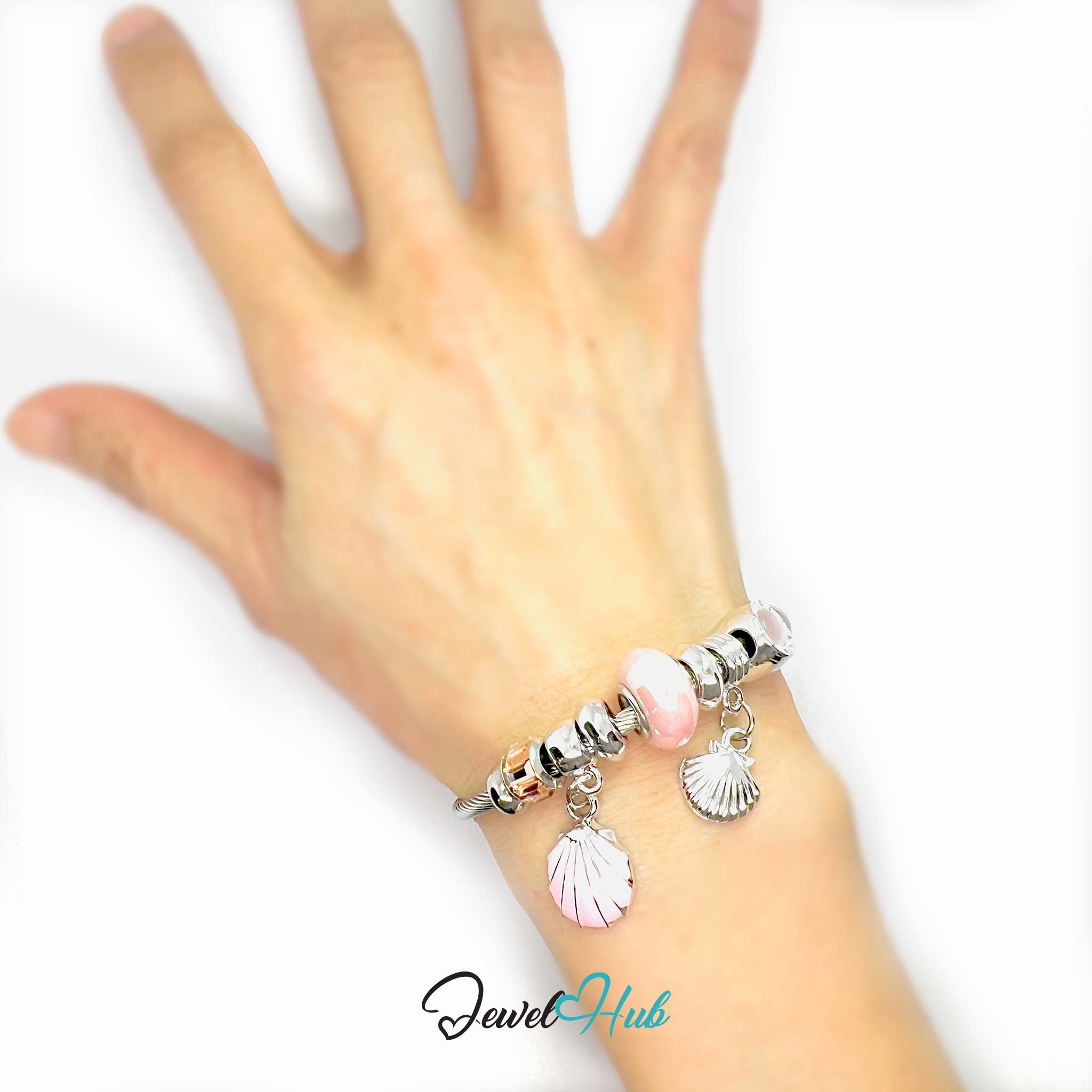 Hand wearing a bracelet with shell charms on a white background, branded 'Jewel Hub'.