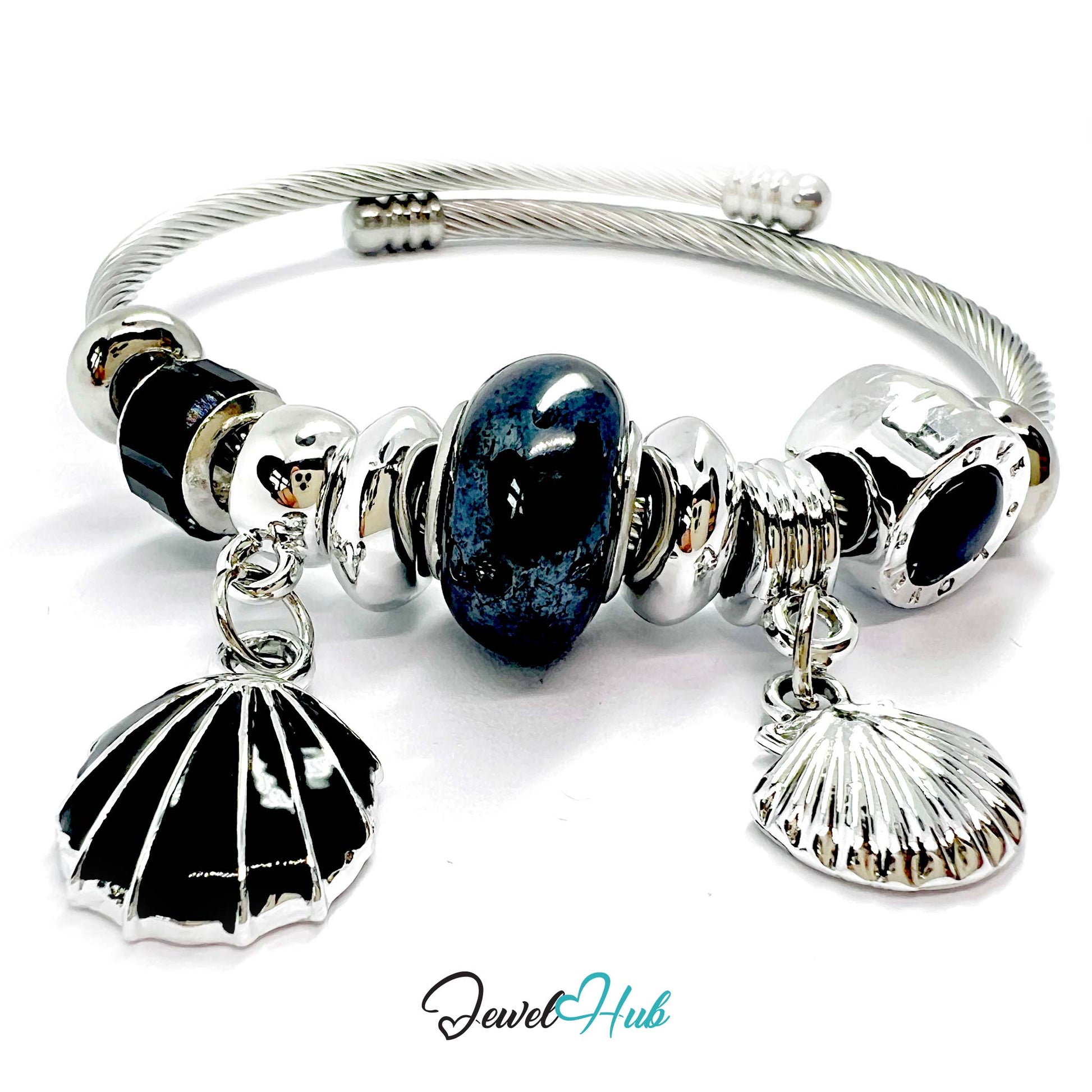 Silver bracelet with black and silver shell charms and a blue heart bead on a white background.