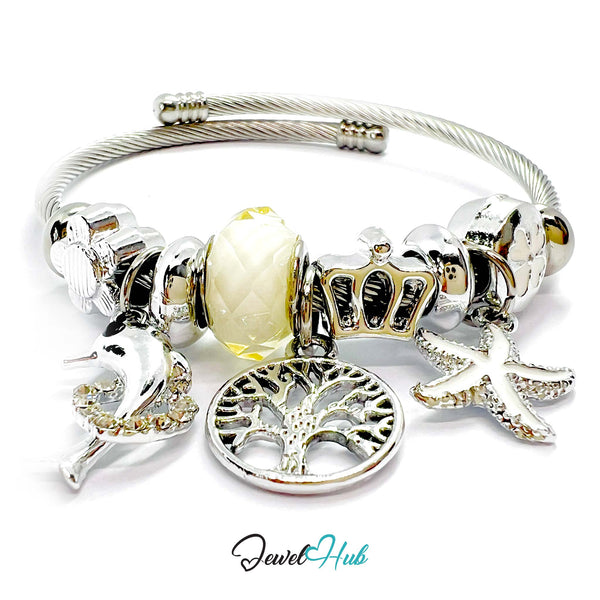 Silver bracelet with various charms including a yellow bead, crown, tree, and starfish on a white background. Brand 'Jewel Hub' visible.