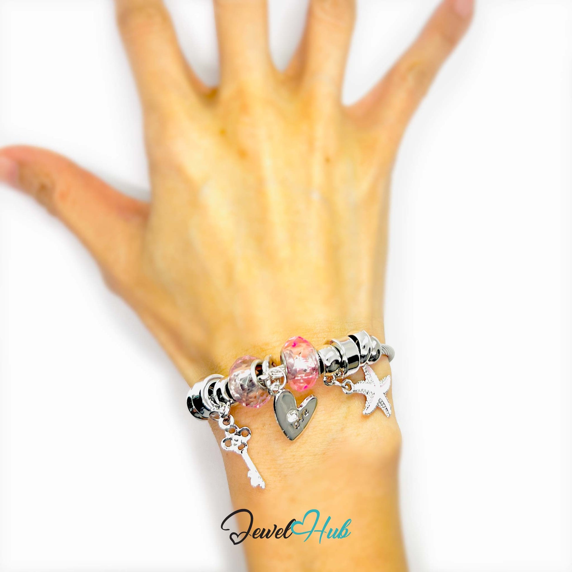 Hand wearing a bracelet with charms on a white background, brand 'Jewel Hub' visible.