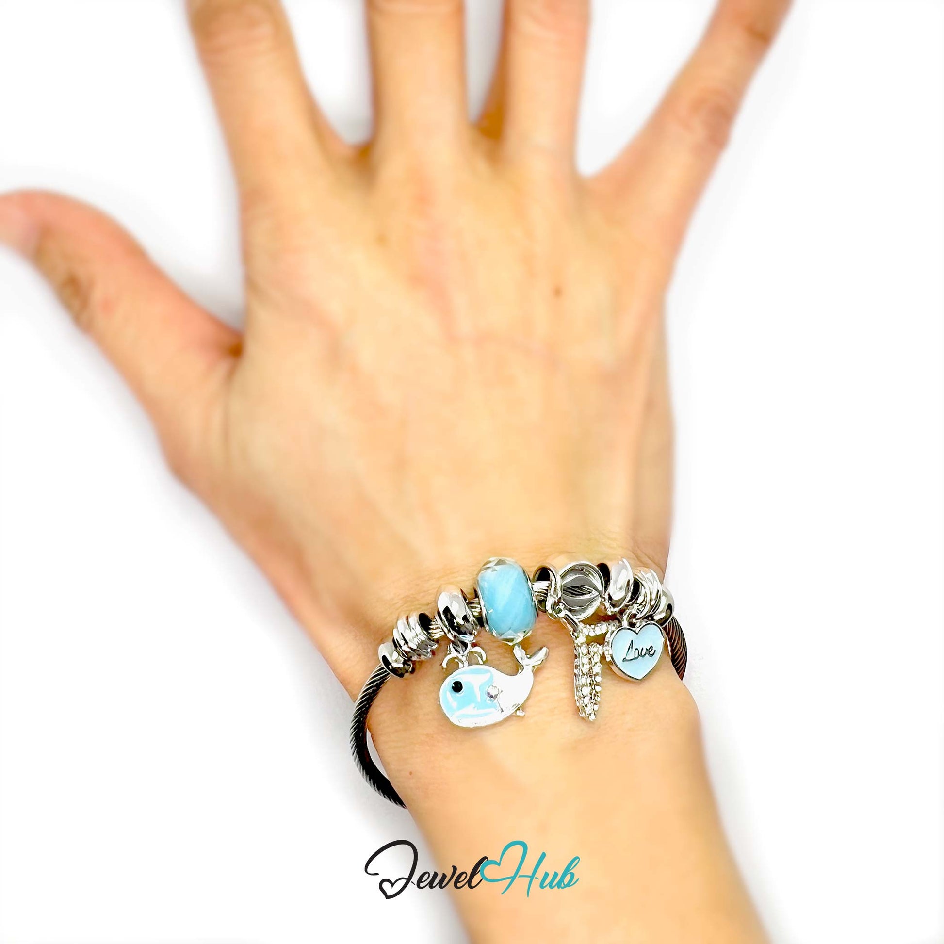 Hand wearing a bracelet with charms on a white background, featuring the brand 'Jewel Hub'.