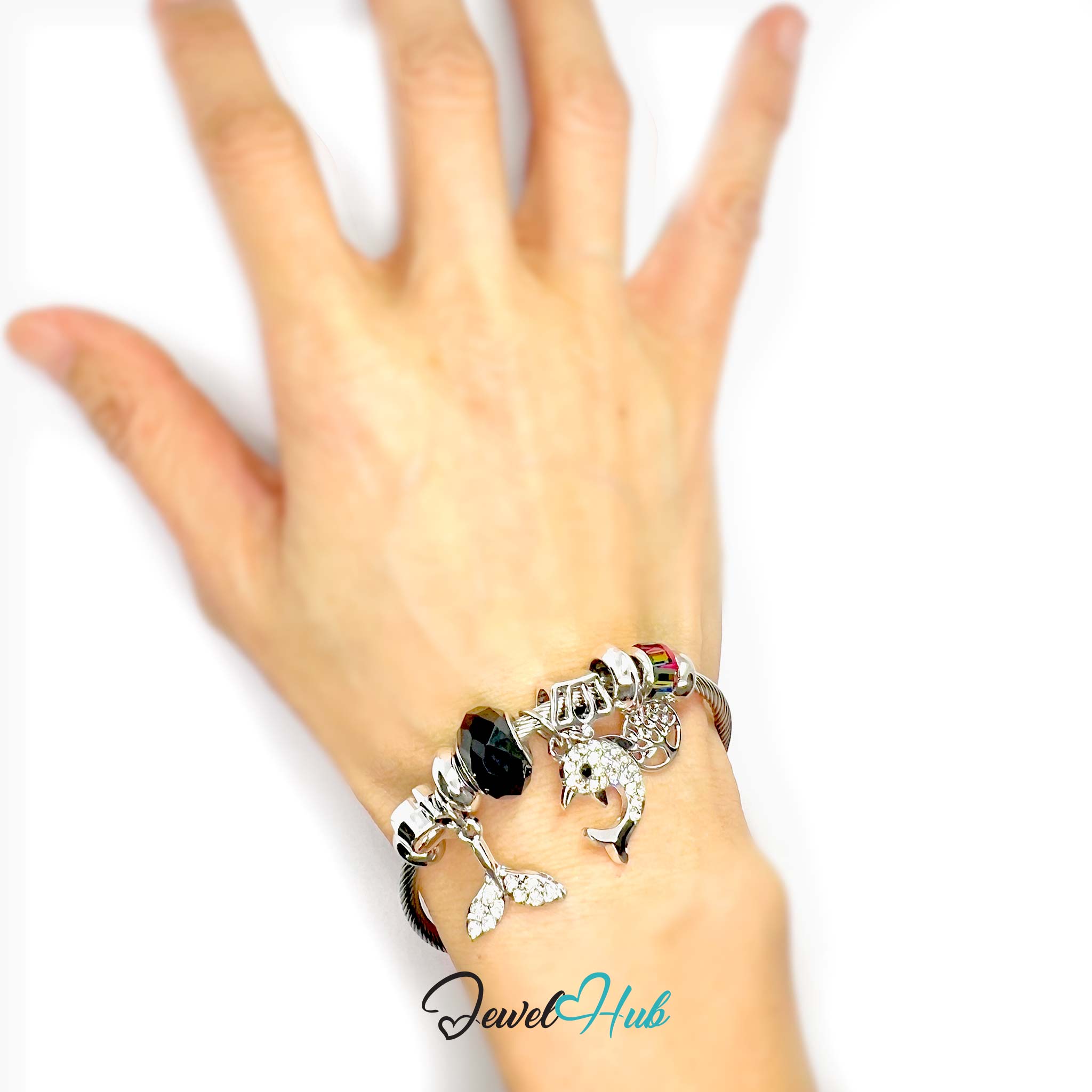 Hand wearing a bracelet with various charms on a white background, featuring the brand 'Jewel Hub'.