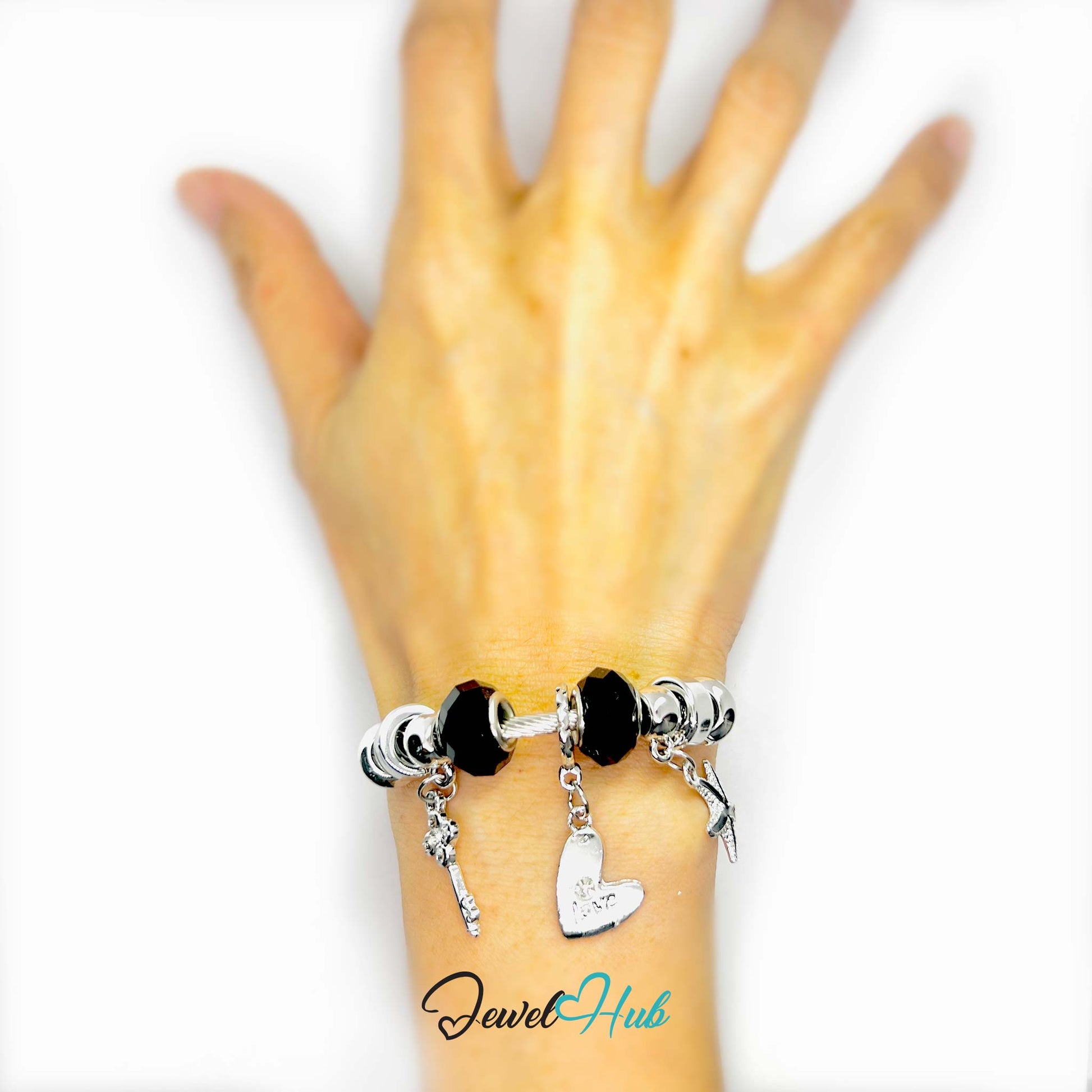 Hand wearing a bracelet with charms on a white background, brand 'Jewel Hub' visible.