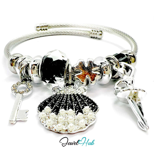 Silver bracelet with various charms including a shell, key, and starfish on a white background.