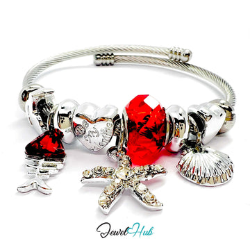 Silver bracelet with various charms including a starfish, shell, and red heart on a white background.