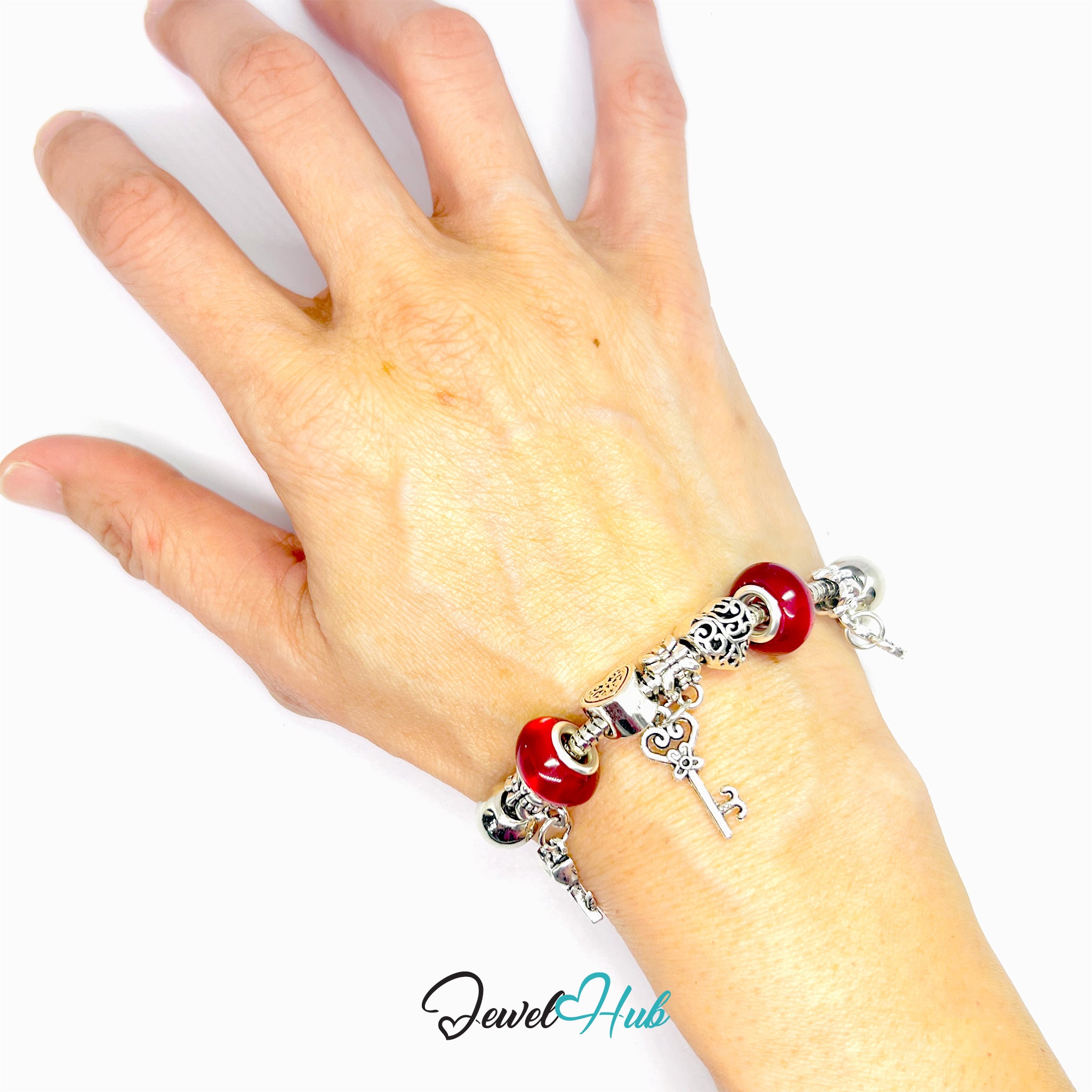 Hand wearing a silver bracelet with red beads on a white background, branded 'Jewel Hub'.