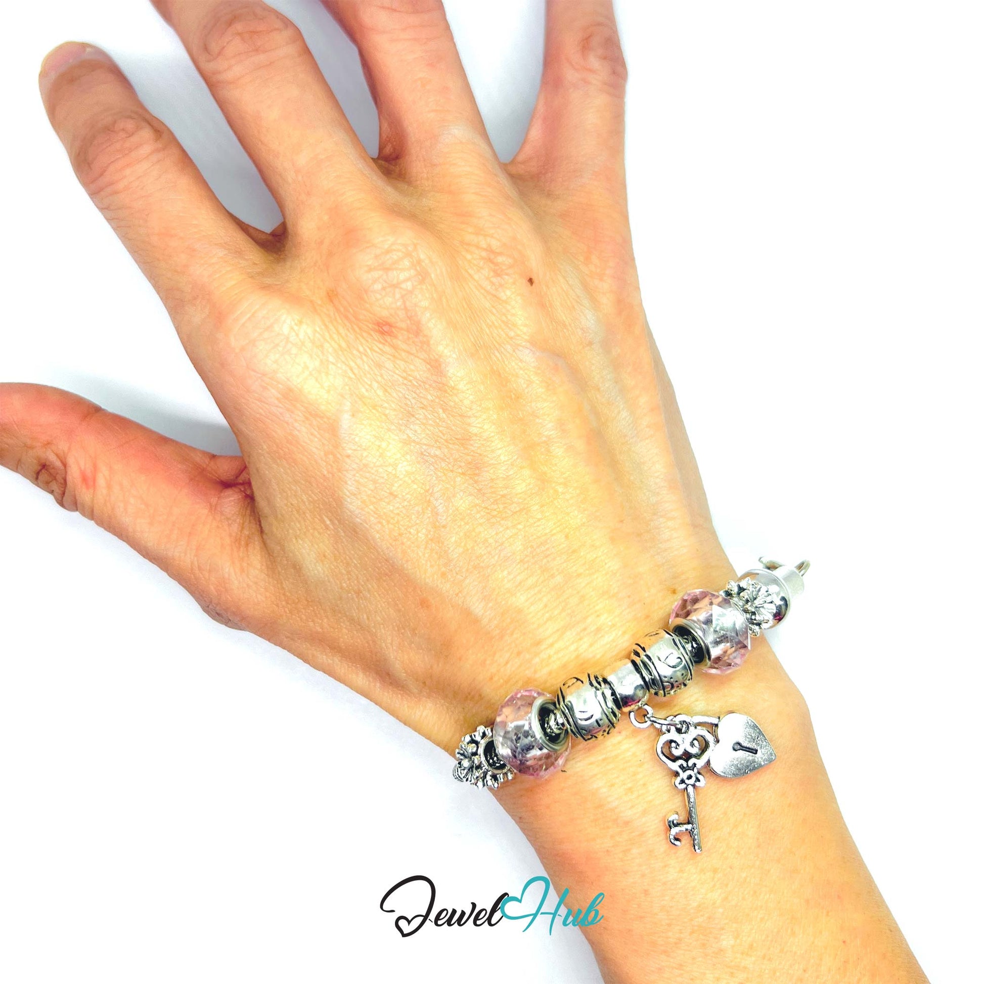 Hand wearing a bracelet with charms on a white background, brand 'Jewel Hub' visible.