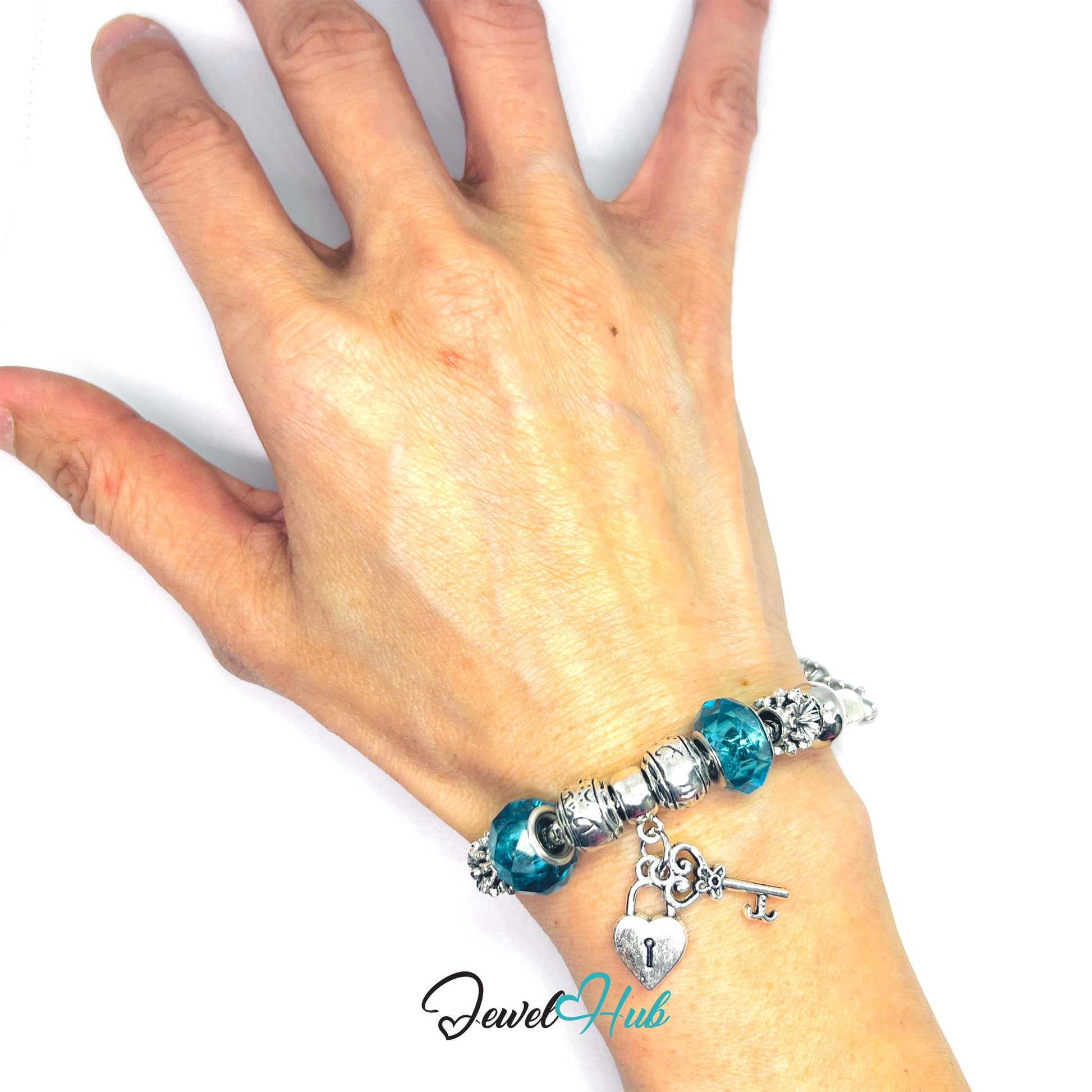 Hand wearing a turquoise beaded bracelet with charms on a white background, branded 'Jewel Hub'.