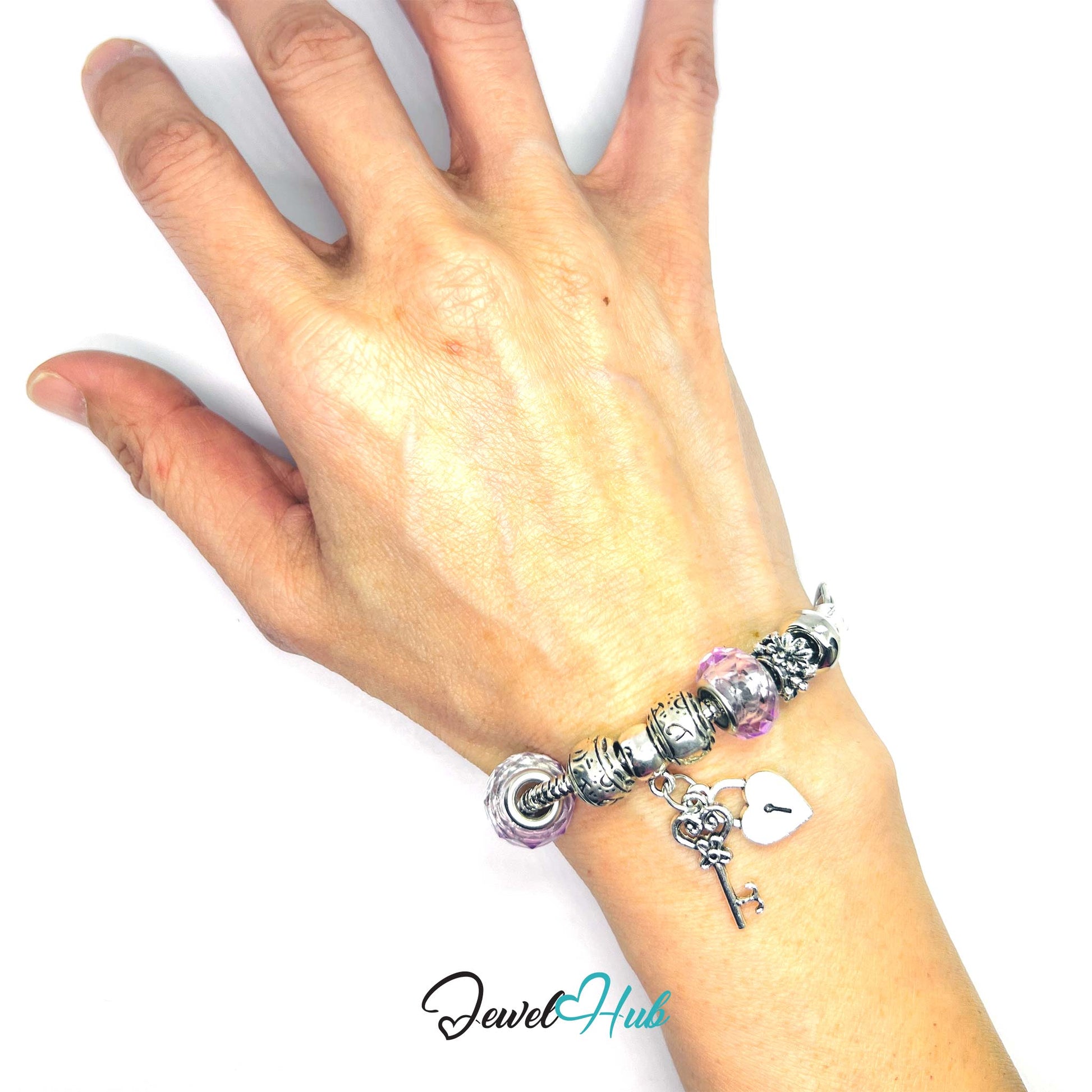 Hand wearing a bracelet with charms on a white background, brand 'Jewel Hub' visible.