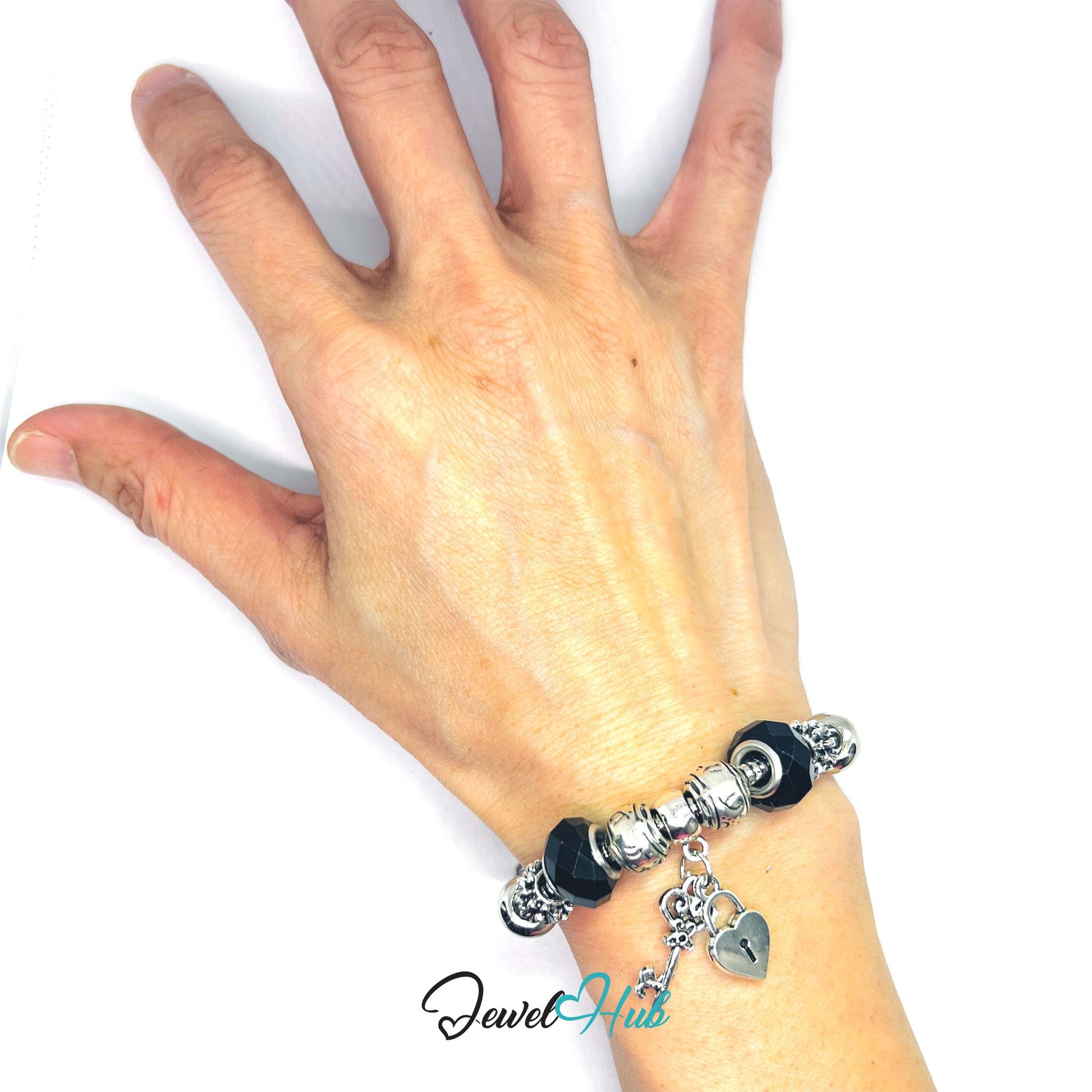 Hand wearing a bracelet with charms on a white background, brand 'Jewel Hub' visible.