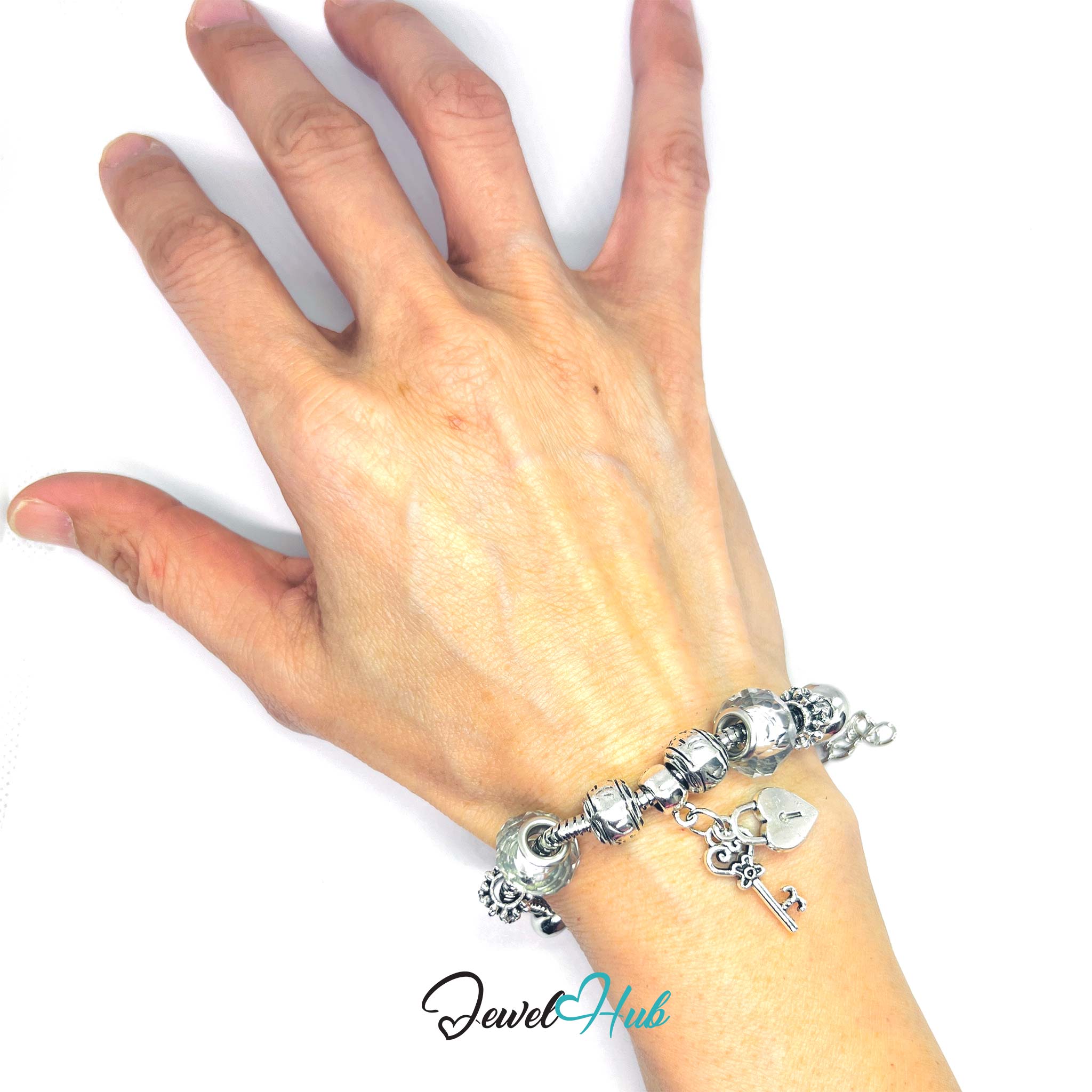 Hand wearing a silver charm bracelet on a white background with 'Jewel Hub' branding.