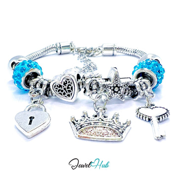 Silver bracelet with various charms including a blue bead, heart, lock, crown, and cloud on a white background. Brand 'Jewel Hub' visible.