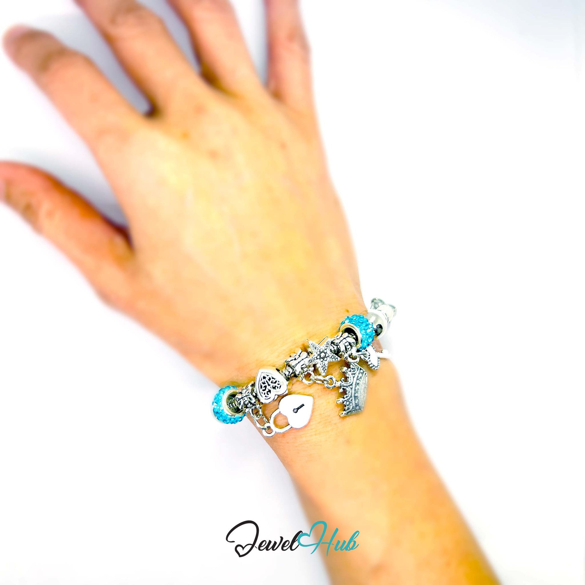 Hand wearing a bracelet with charms on a white background, branded 'Jewel Hub'.