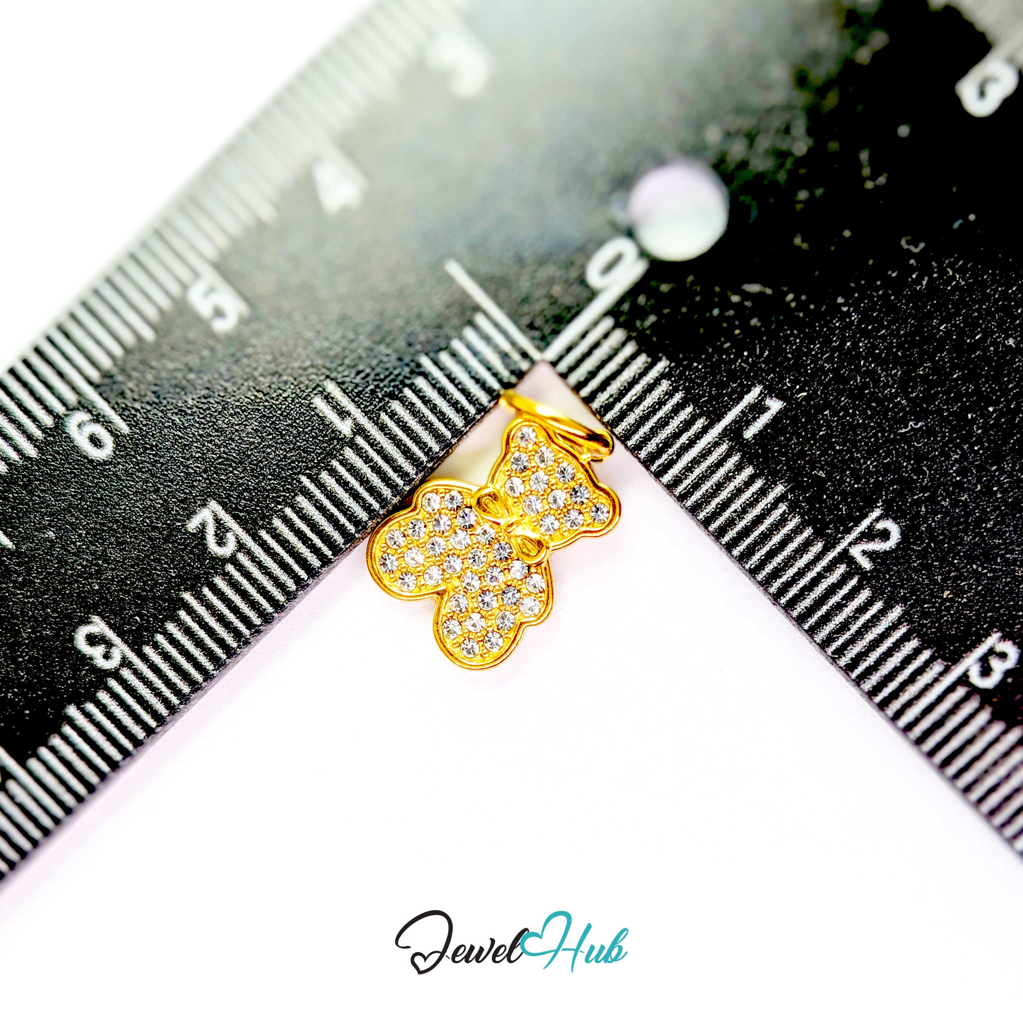 A small gold butterfly-shaped jewelry charm covered with clear rhinestones, shown on a white background with a black ruler for scale. The 'JewelHub' logo is visible at the bottom.