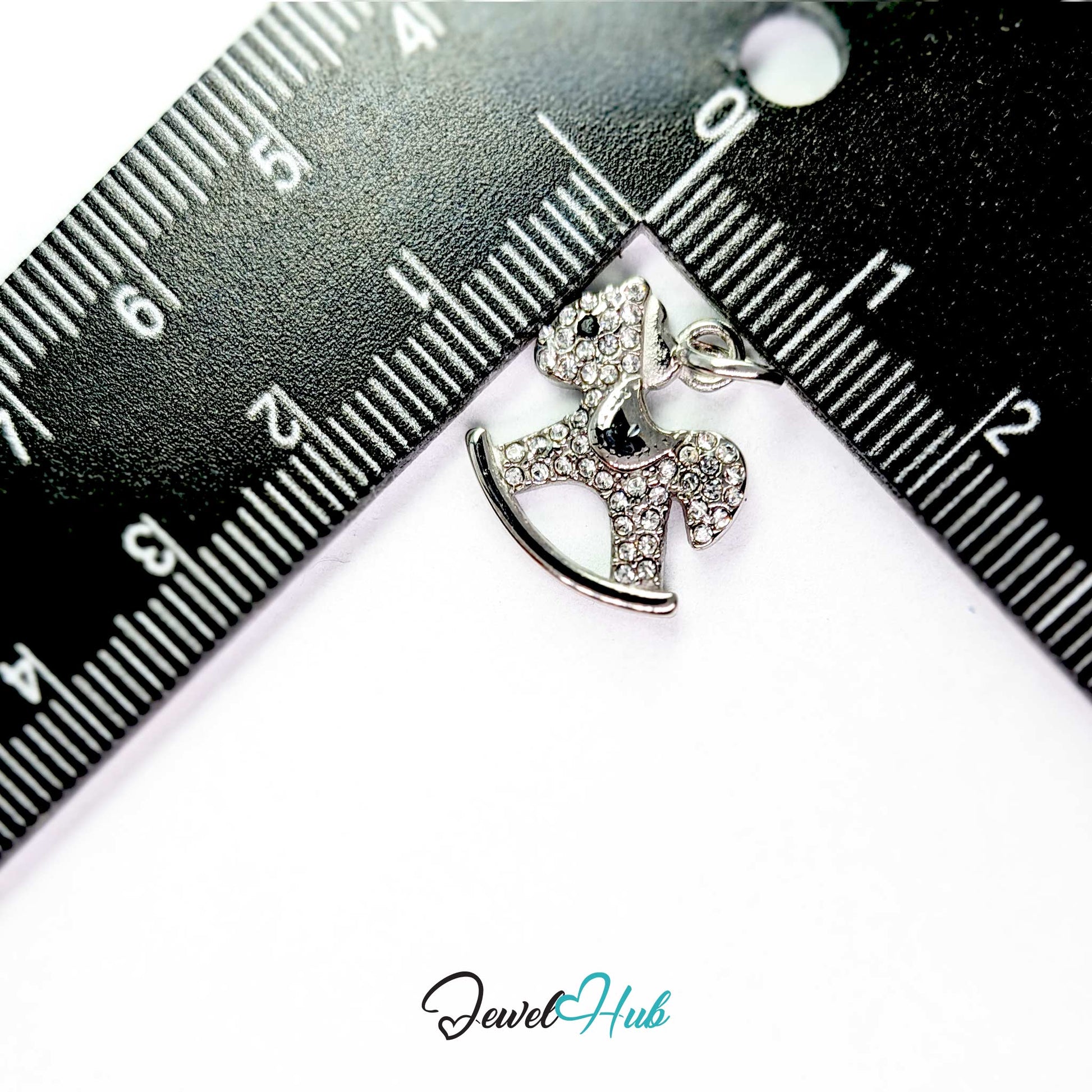 Silver rocking horse charm measured against a ruler at 15.5mm wide by 16.5mm tall - JewelHub