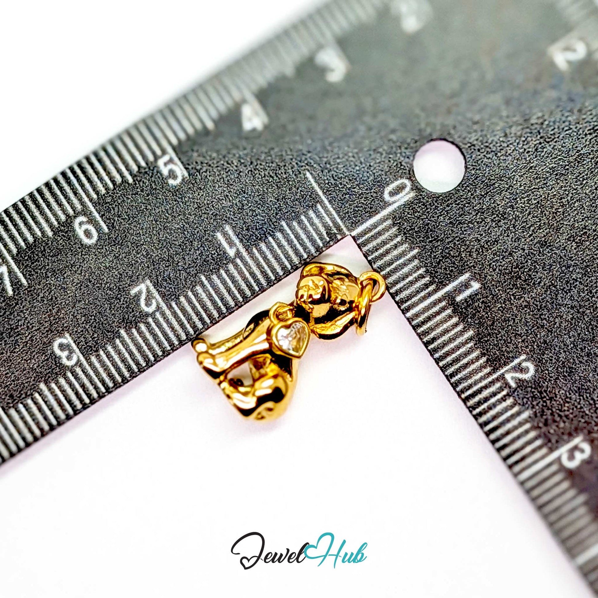Gold sitting puppy charm measured against a ruler at 10.7mm wide by 19.6mm tall - JewelHub