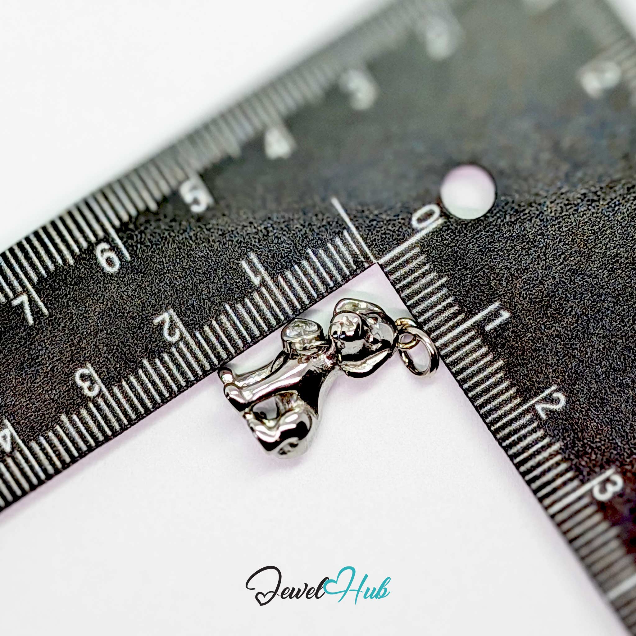 Silver sitting puppy charm measured against a ruler at 10.7mm wide by 19.6mm tall - JewelHub