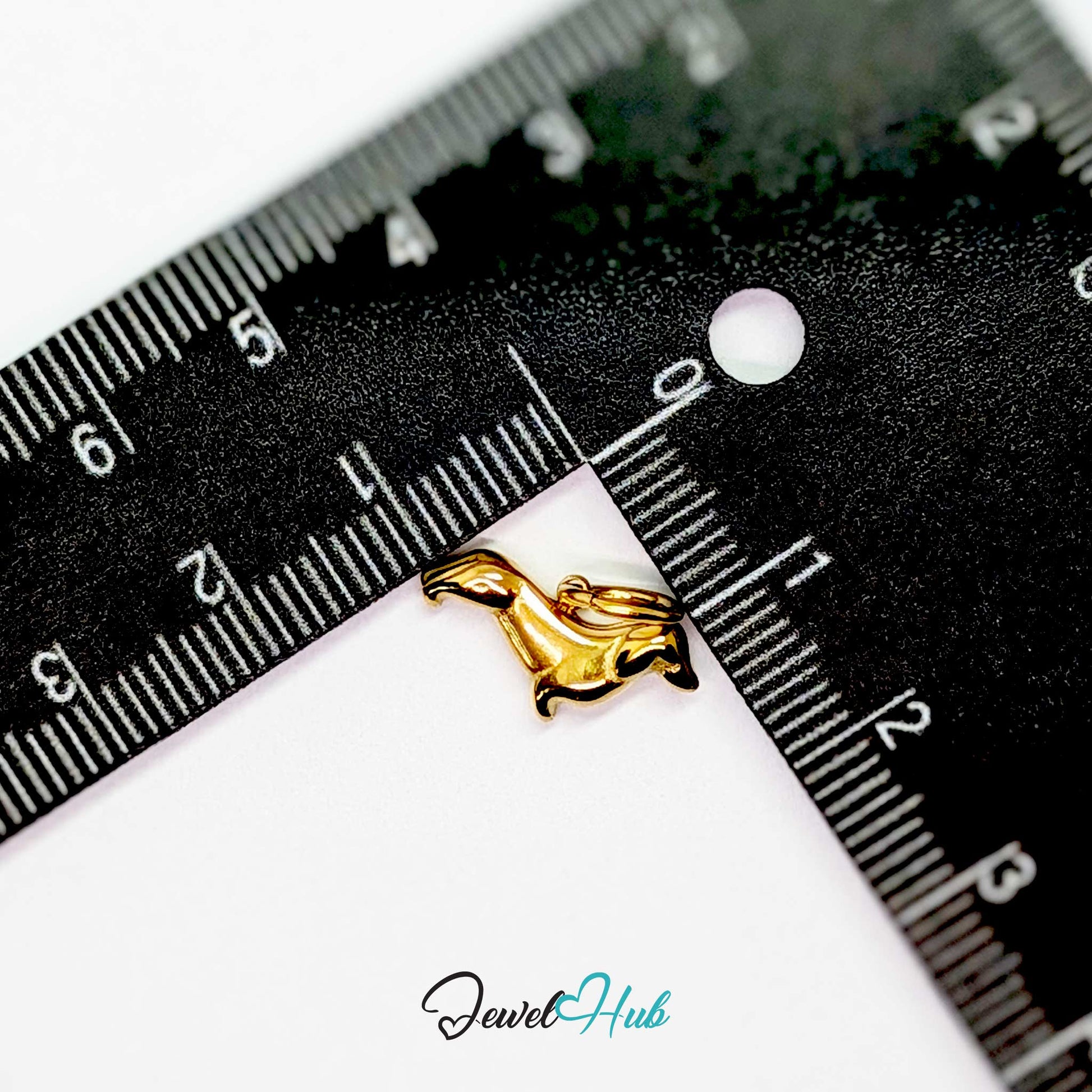 Gold dachshund charm measured against a ruler at 16mm long by 9.8mm tall - JewelHub