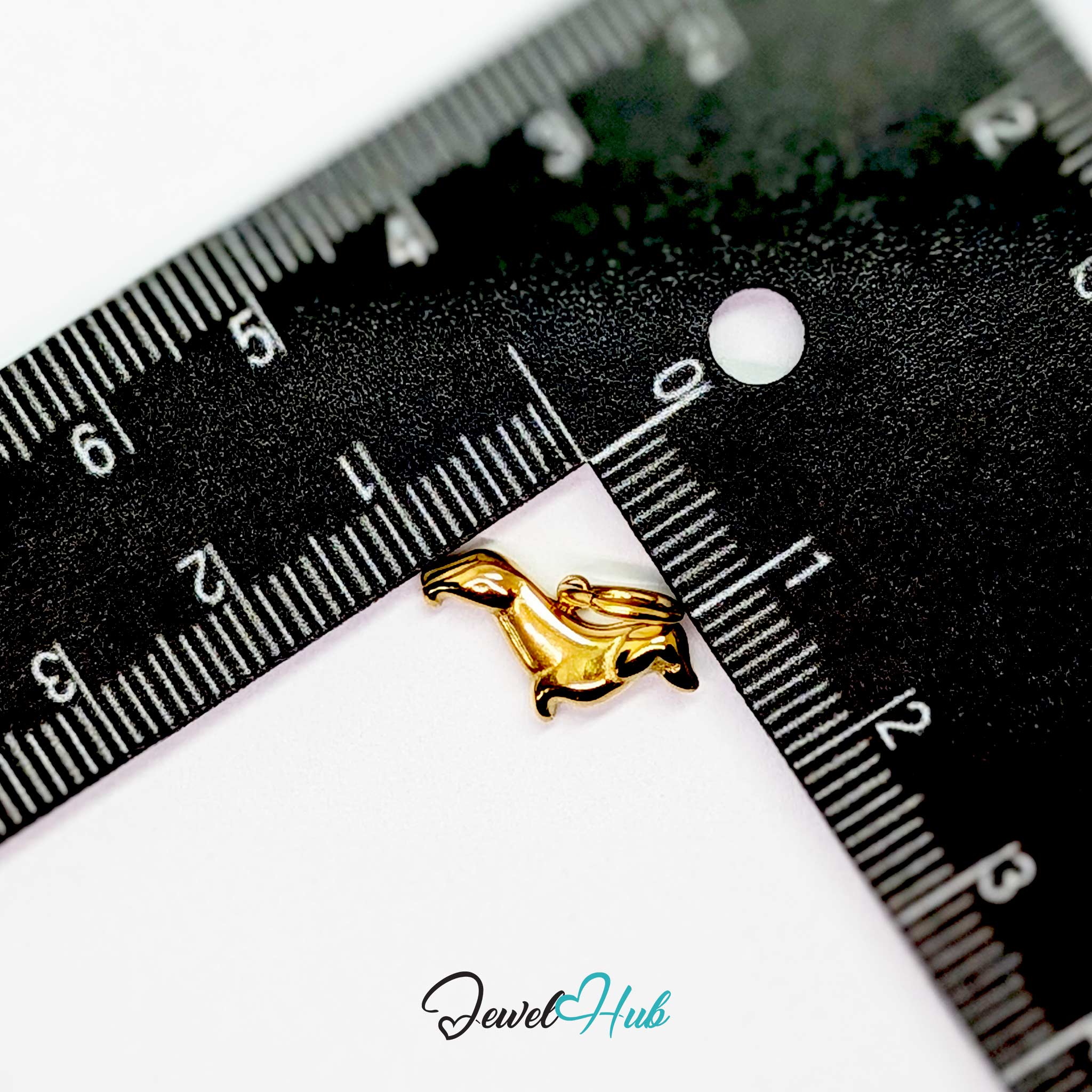 Gold dachshund charm measured against a ruler at 16mm long by 9.8mm tall - JewelHub