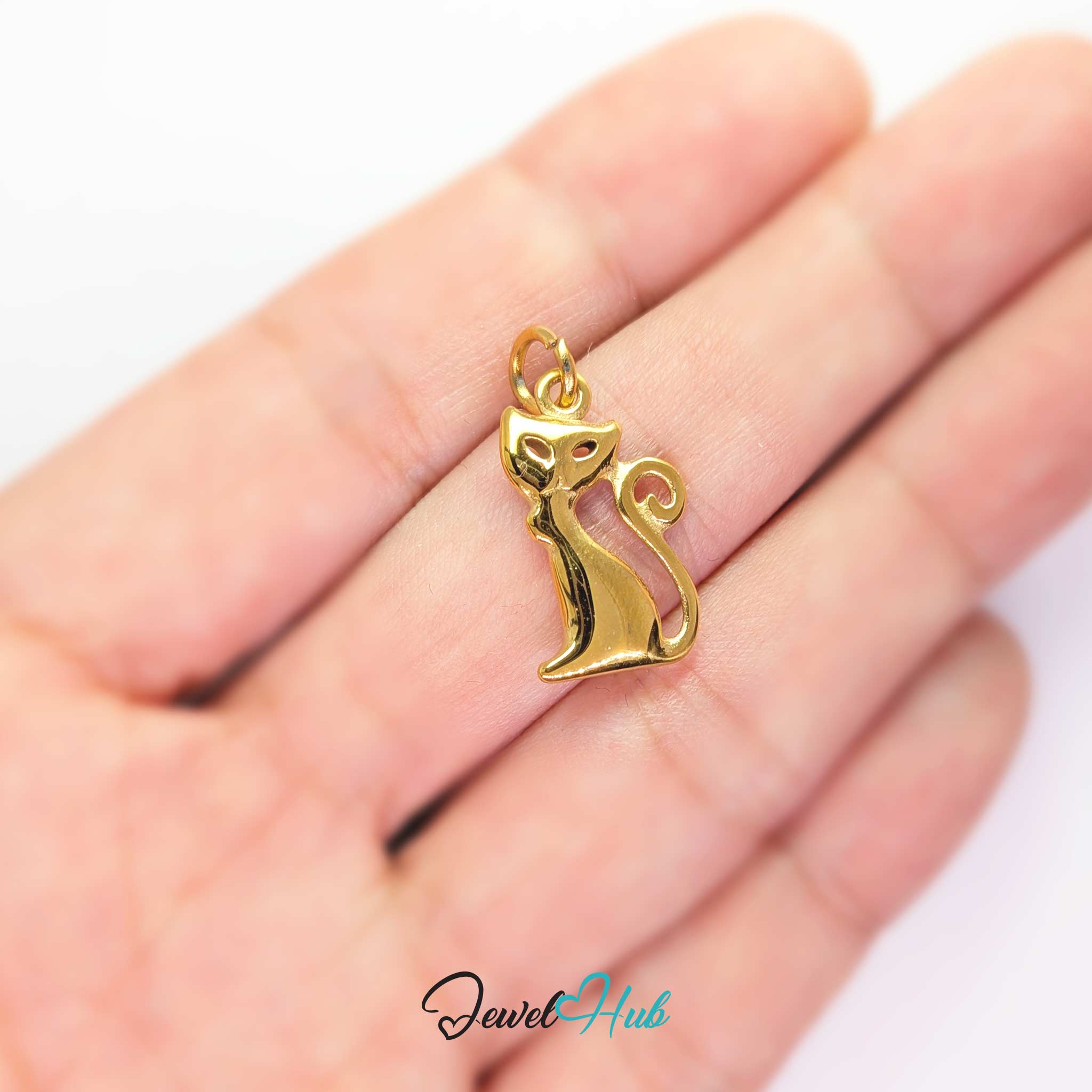 Gold standing cat charm held in the hand to show its size against a fingertip - JewelHub