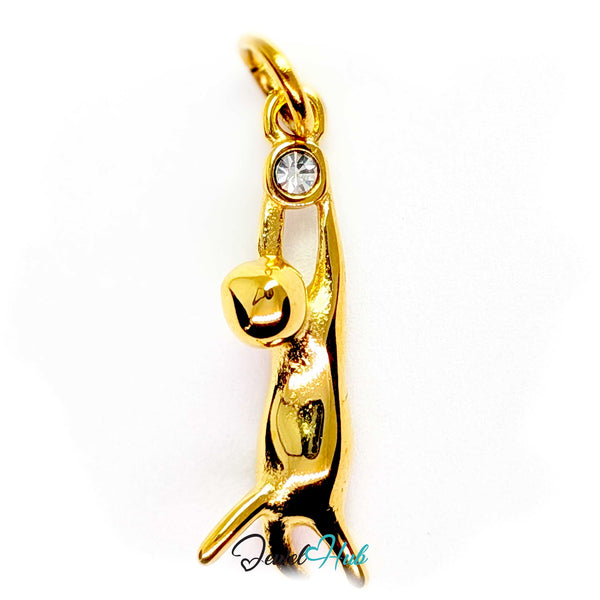 Gold cat charm hanging by its front paws from a bezel-set clear crystal - JewelHub