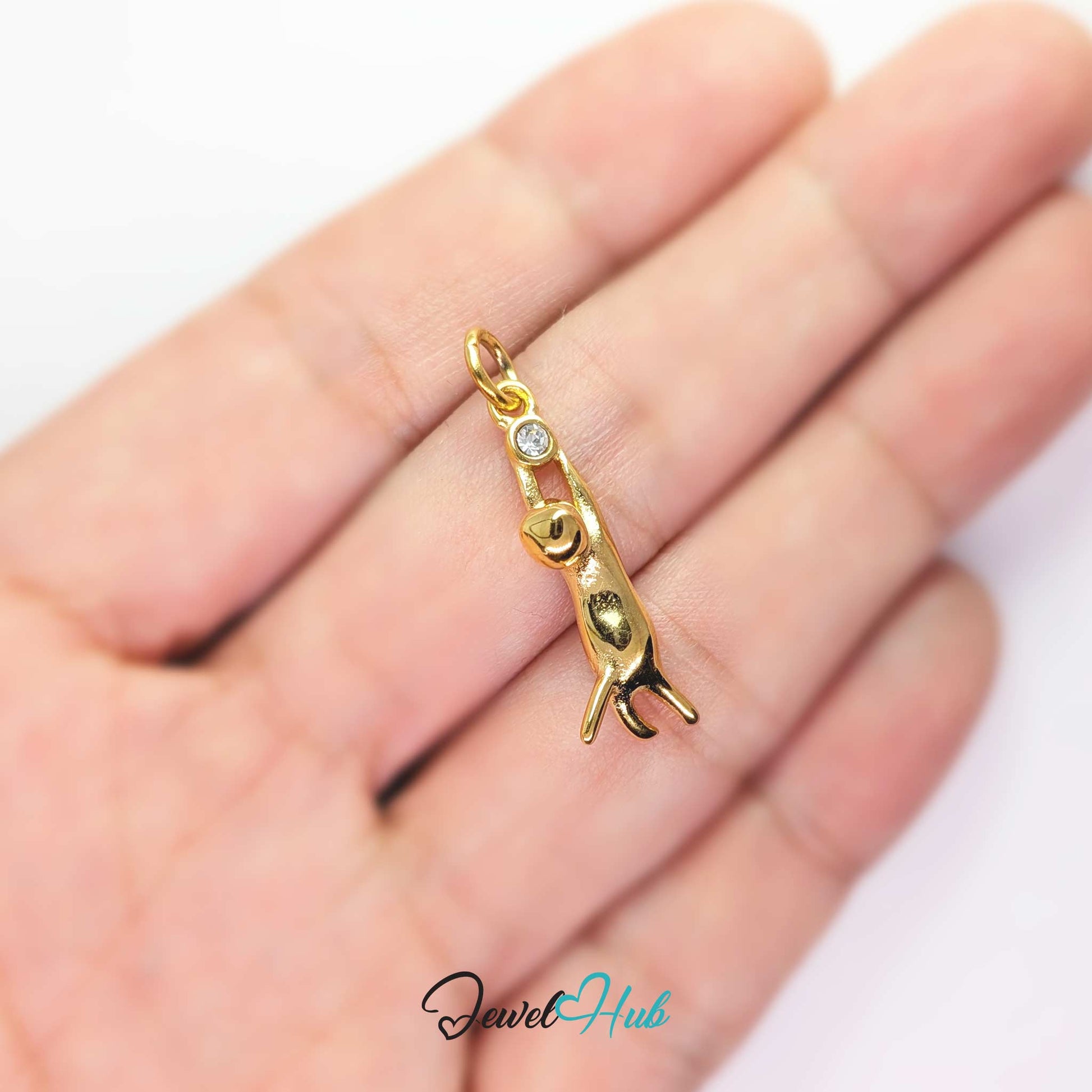 Gold hanging cat charm held in the hand to show its long narrow drop - JewelHub