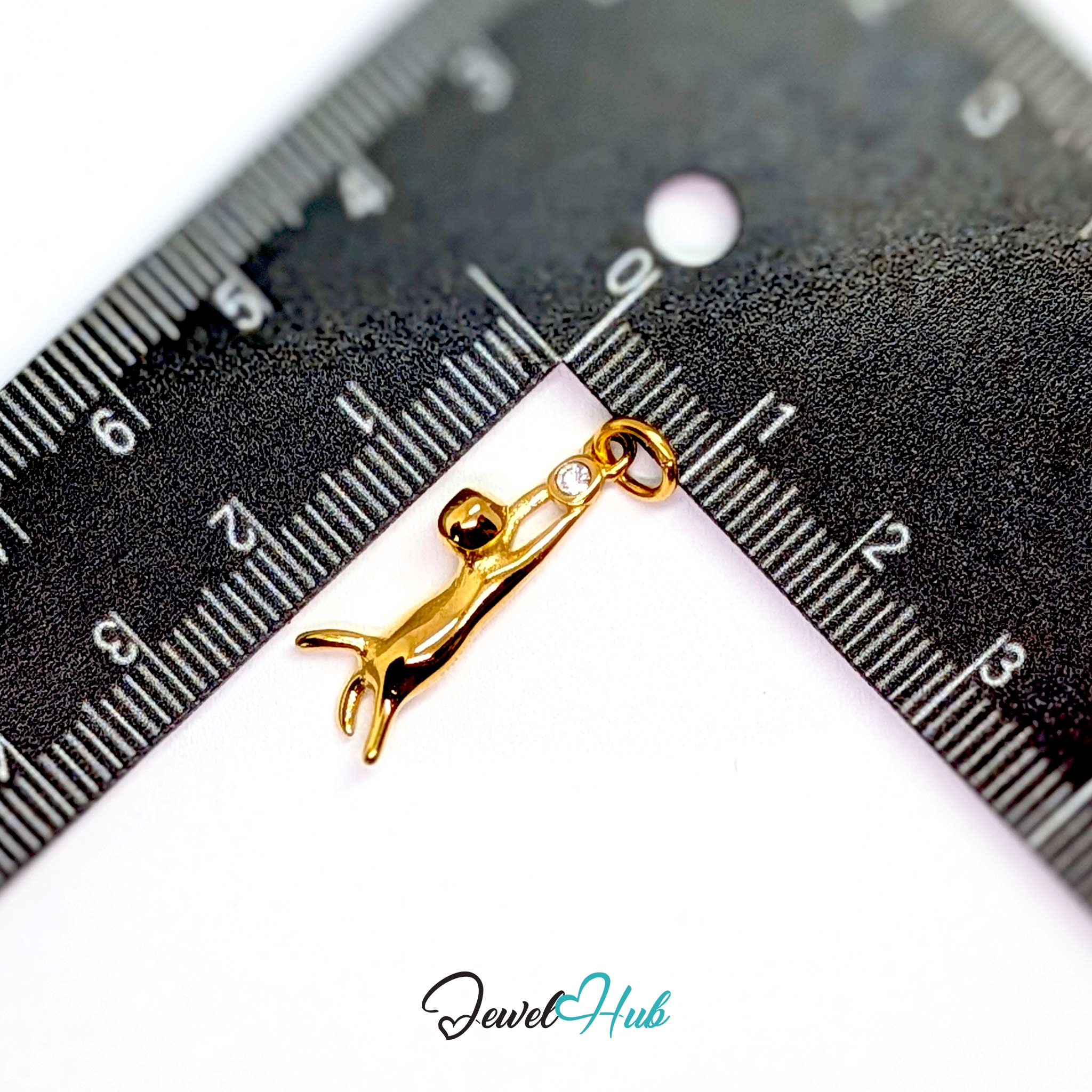 Gold hanging cat charm measured against a ruler at 25mm tall by 6.2mm wide - JewelHub