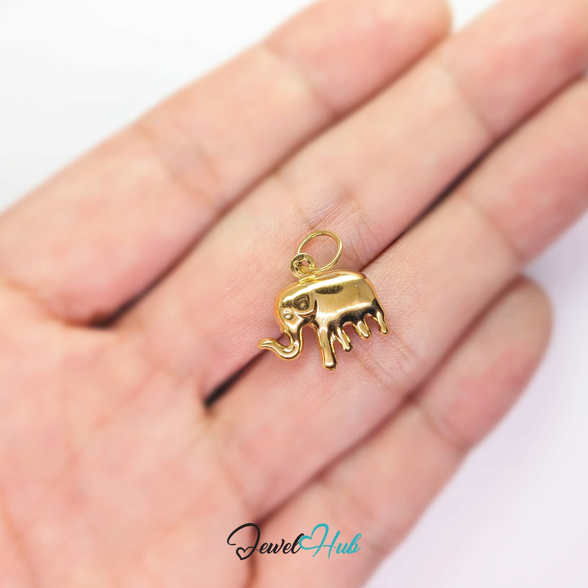 Gold elephant charm held in the hand to show its size against a fingertip - JewelHub