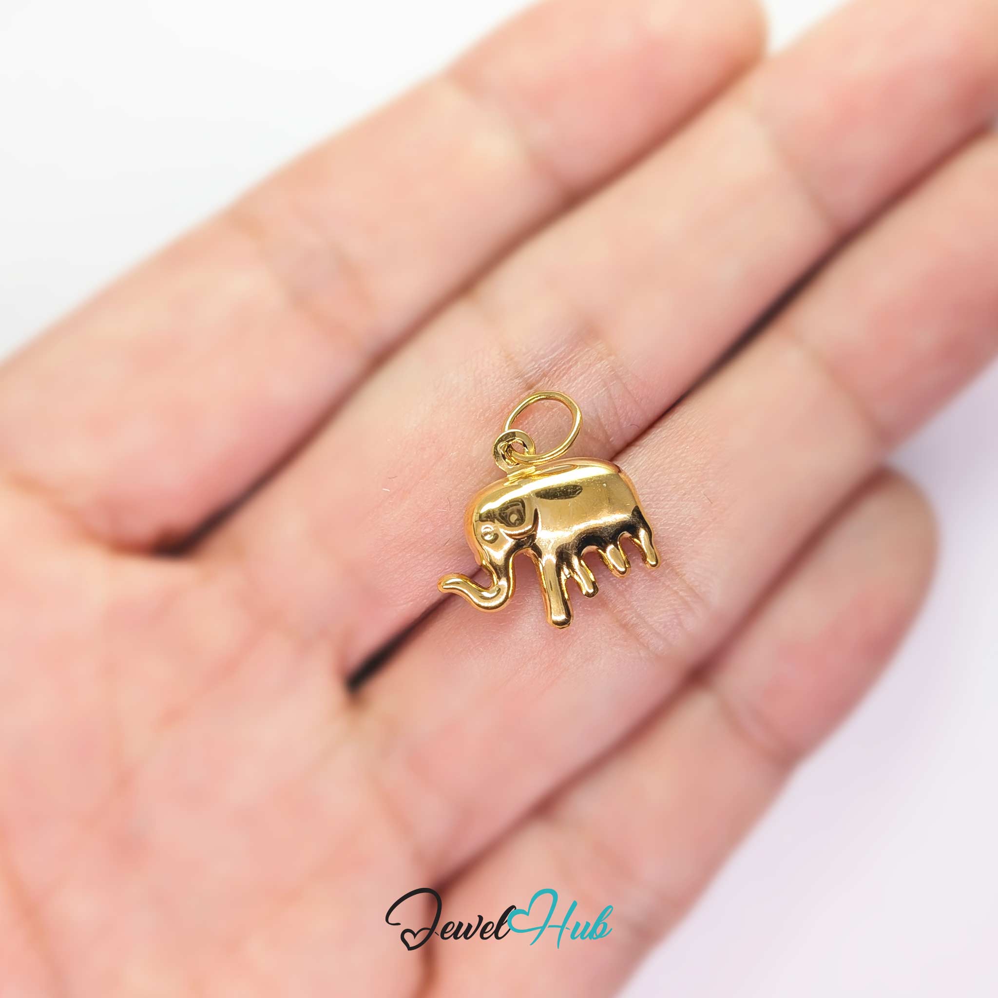 Gold elephant charm held in the hand to show its size against a fingertip - JewelHub