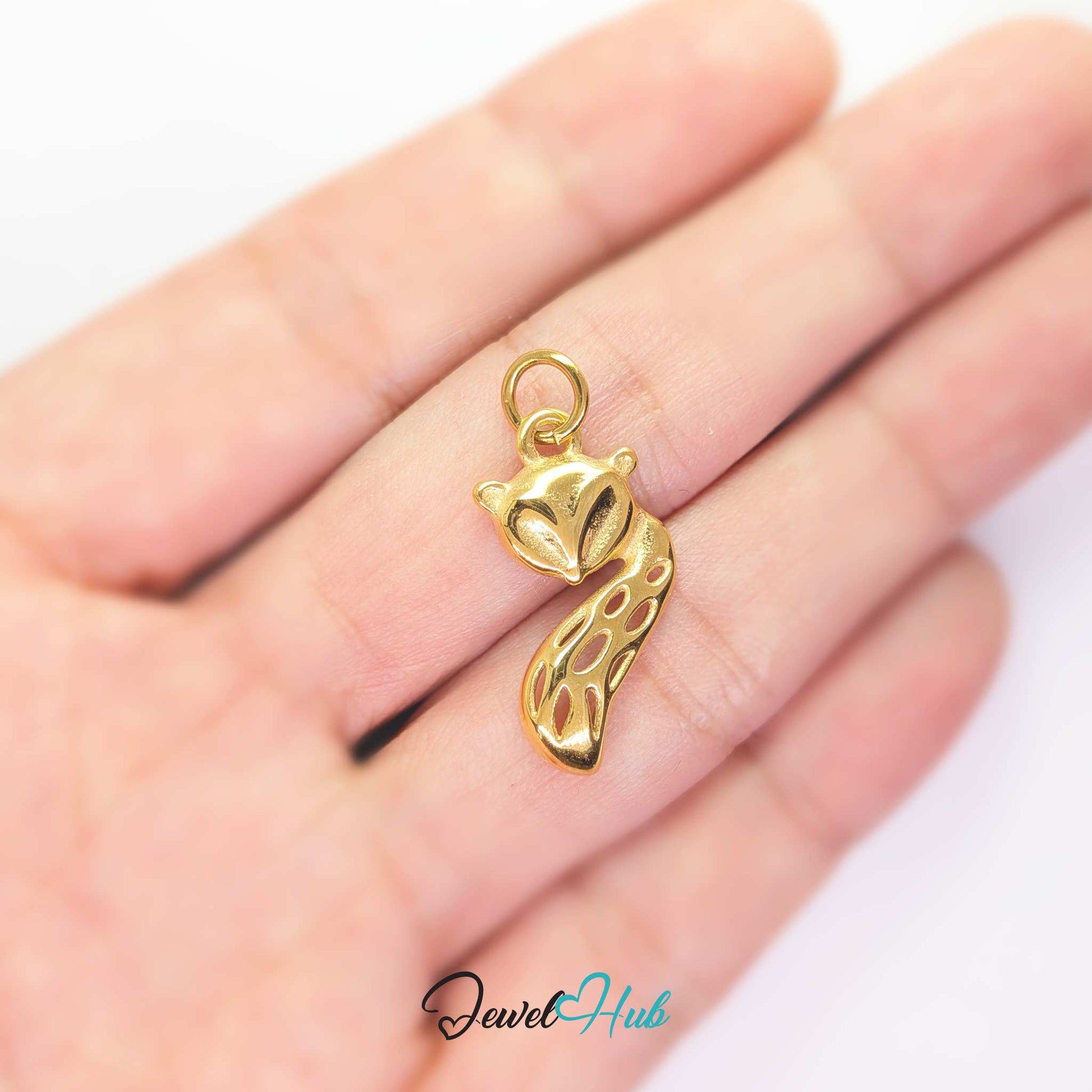 Gold fox charm held in the hand to show its size against a fingertip - JewelHub