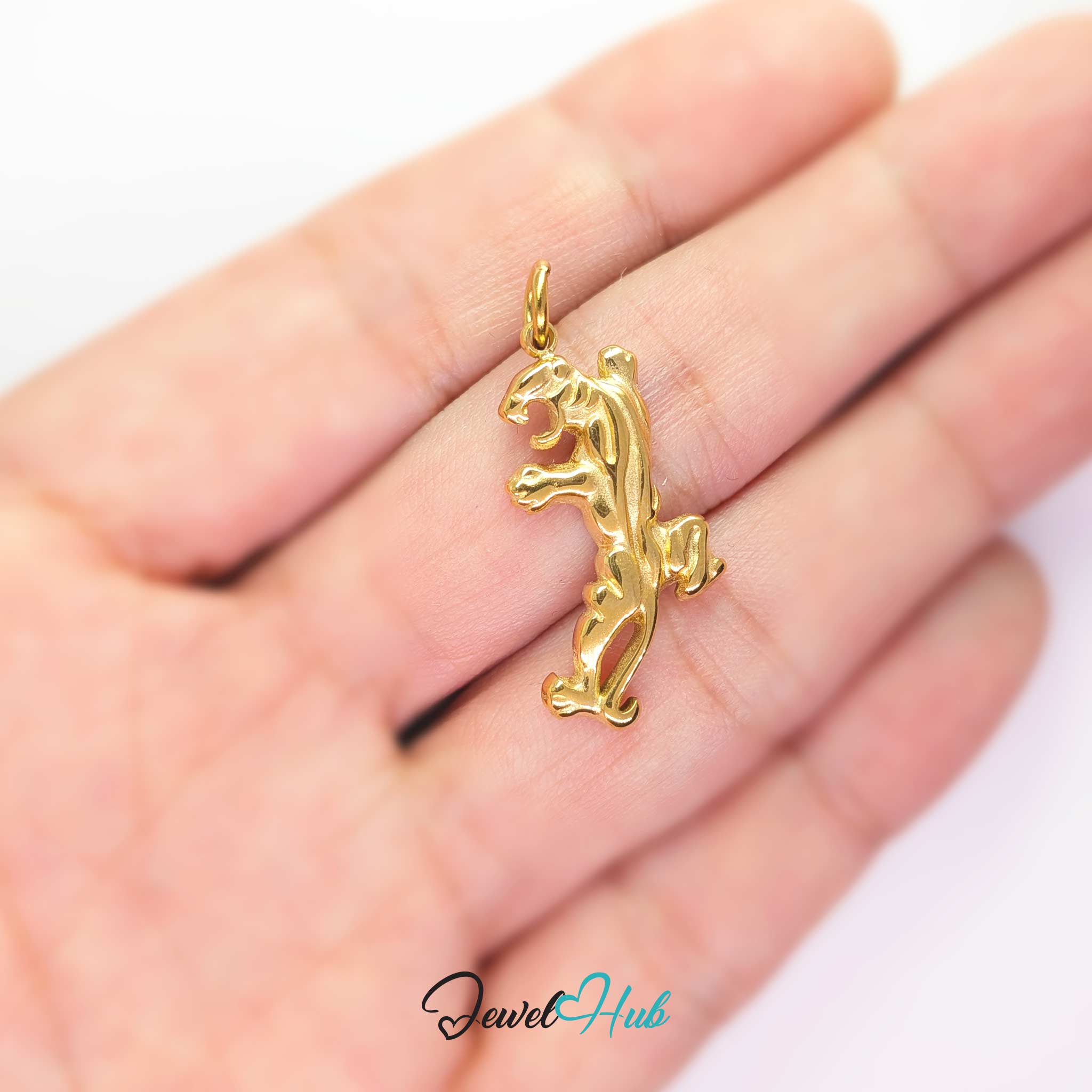 Gold tiger charm held in the hand to show its size against a fingertip - JewelHub