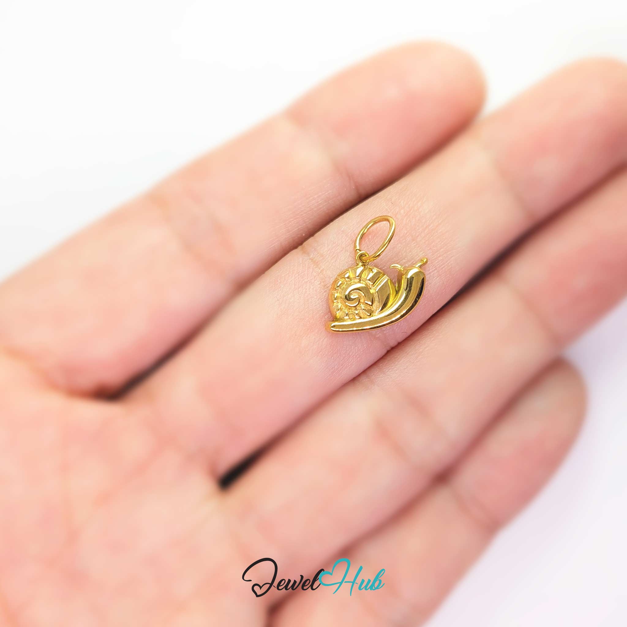 Gold snail charm held in the hand to show how small and light it is - JewelHub