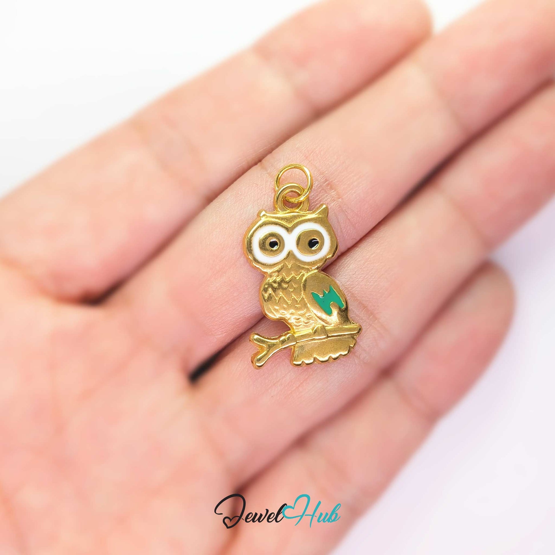 Gold enamel owl charm held in the hand to show its size against a fingertip - JewelHub