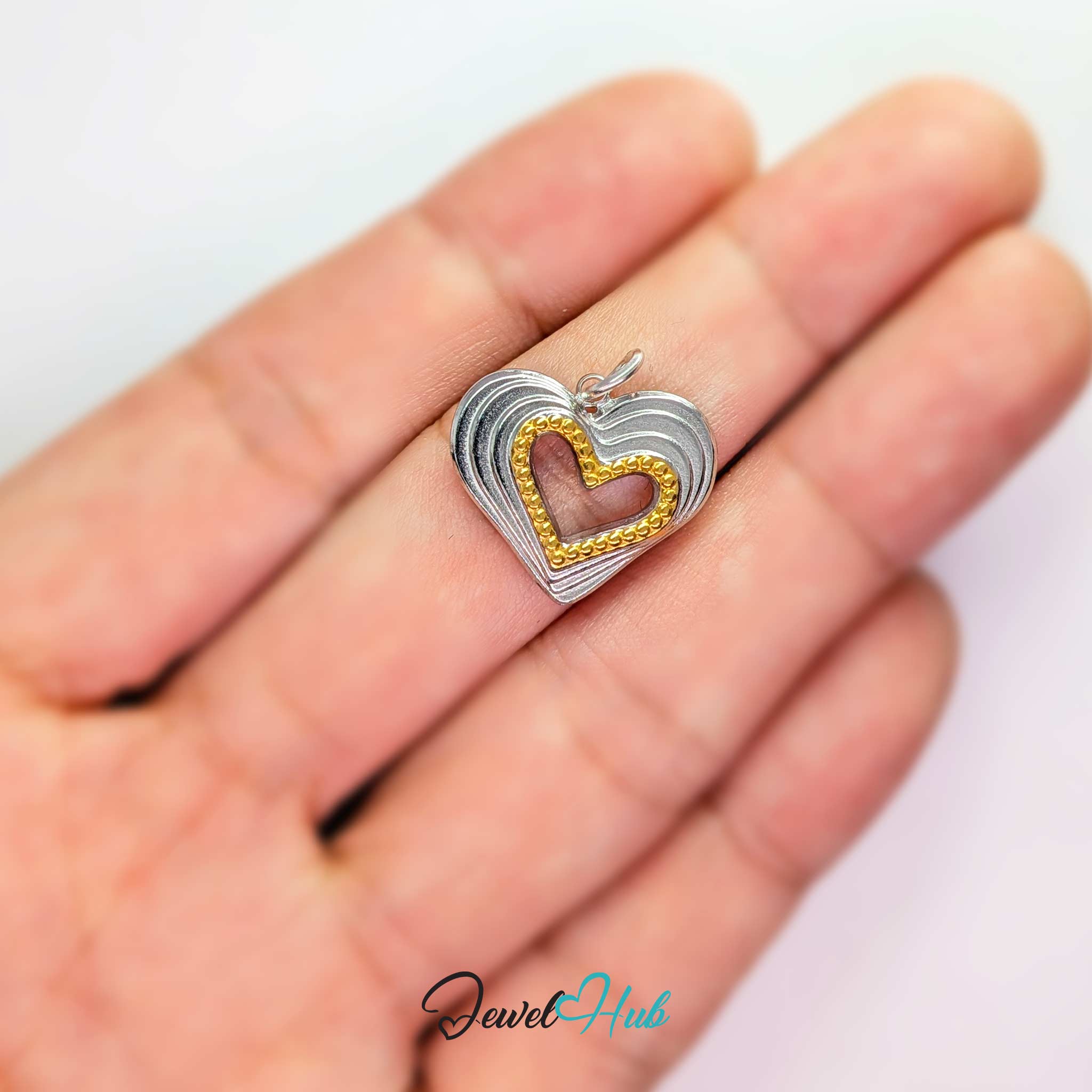 Hollow Heart charm, two-tone stainless steel, held in the hand to show its size - JewelHub