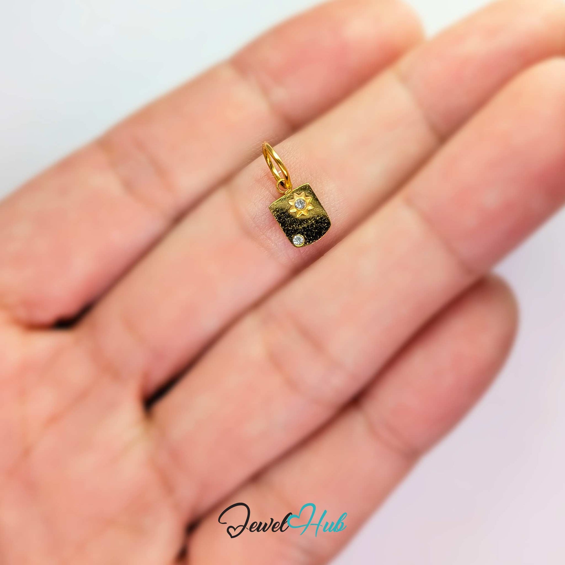 Mini Star Shield charm, gold stainless steel, held in the hand to show its size - JewelHub