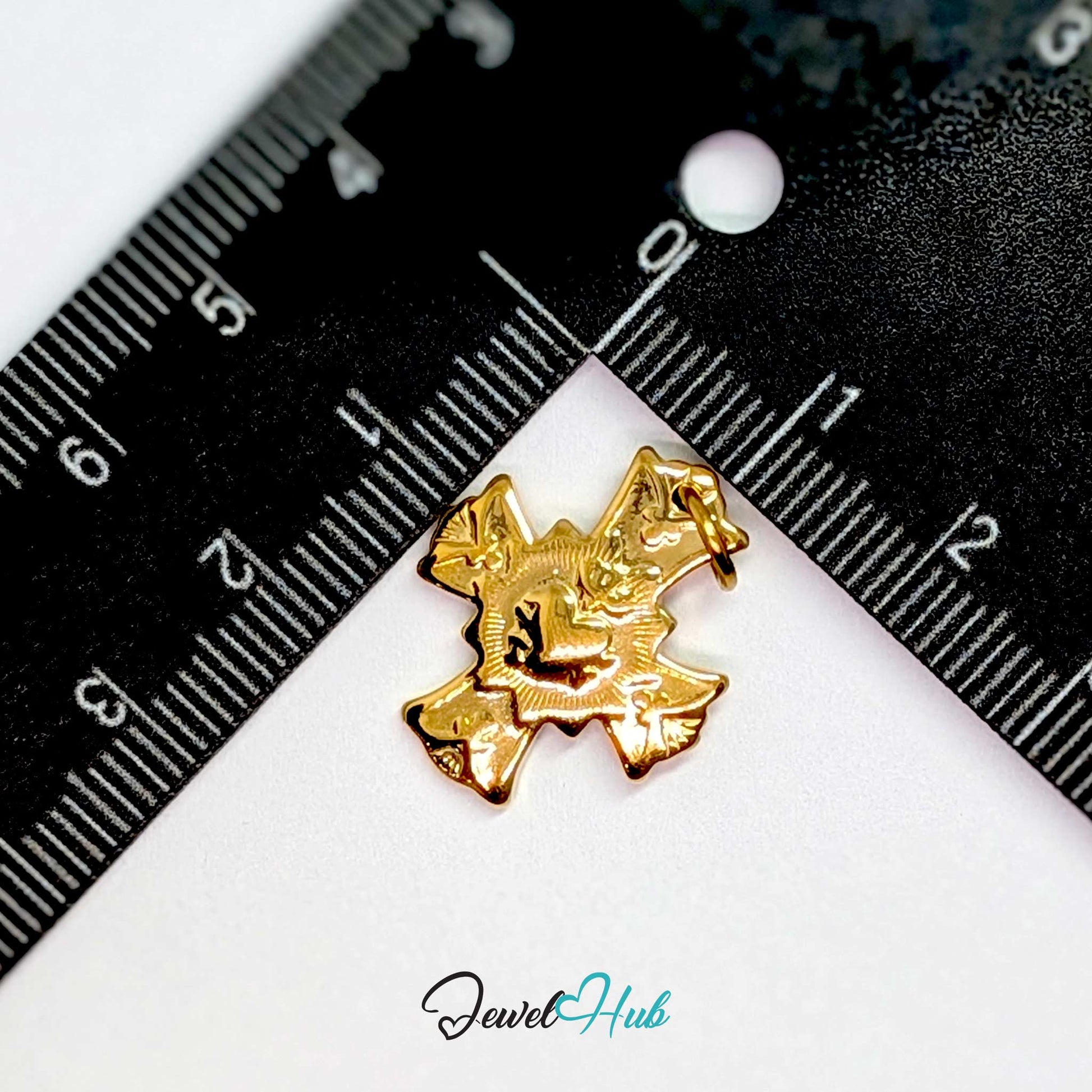 Dove cross charm in gold stainless steel with a radiant heart - beside a ruler for scale - JewelHub
