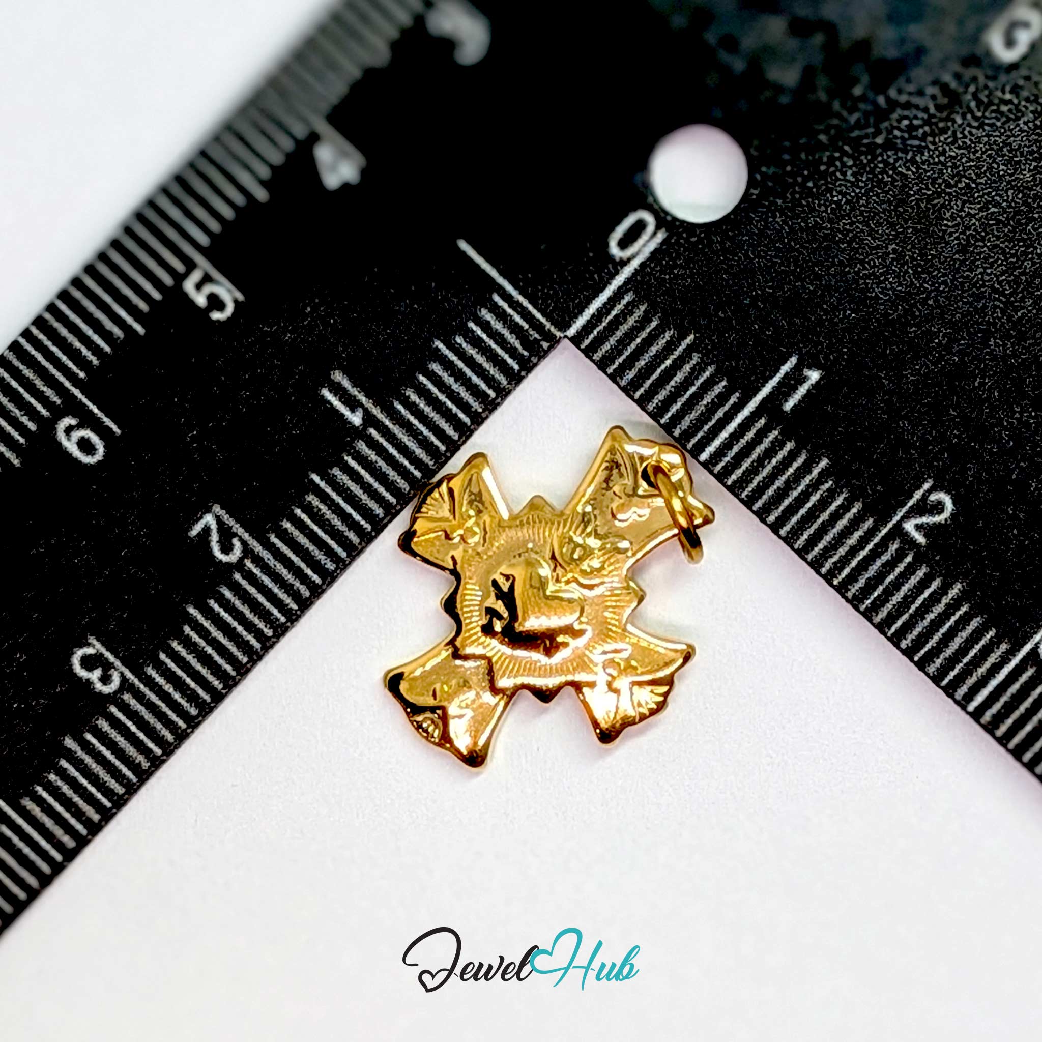 Dove cross charm in gold stainless steel with a radiant heart - beside a ruler for scale - JewelHub
