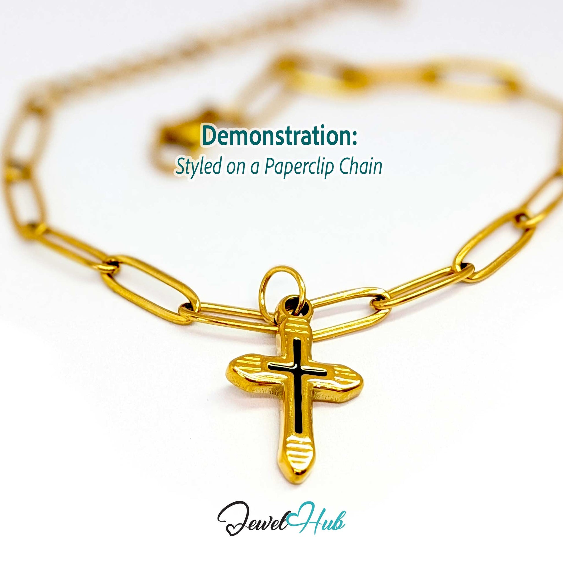 Cross charm in gold stainless steel with a black enamel inlay - styled on a gold paperclip chain bracelet - JewelHub