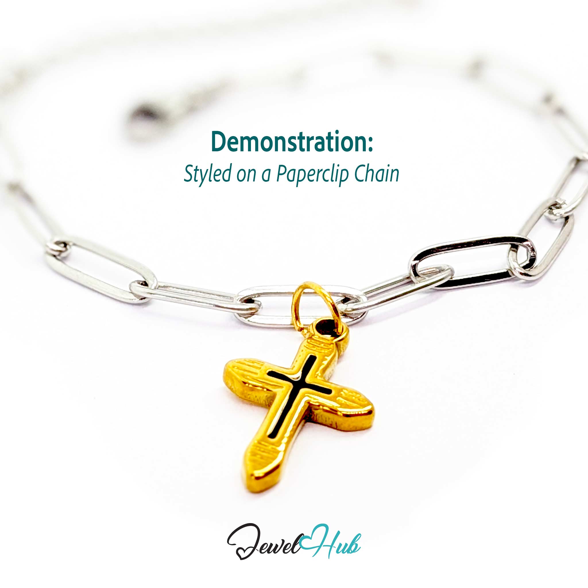 Cross charm in gold stainless steel with a black enamel inlay - styled on a silver paperclip chain bracelet - JewelHub