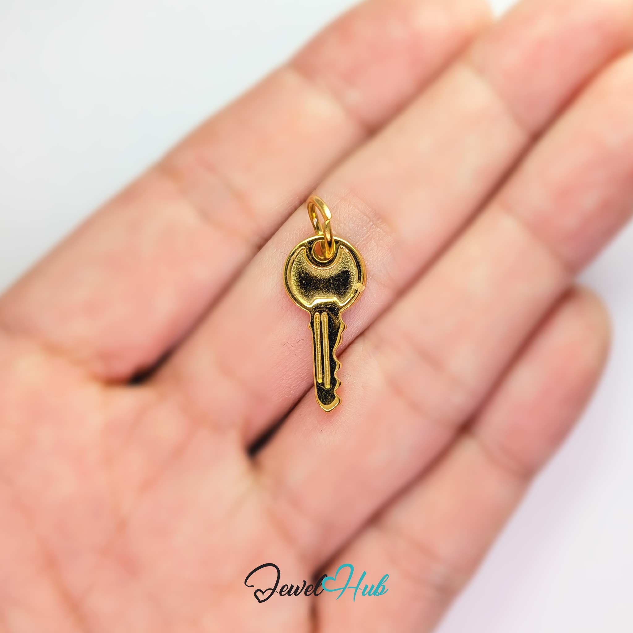 Everyday key charm in gold stainless steel with a plain round head - held in the hand for scale - JewelHub