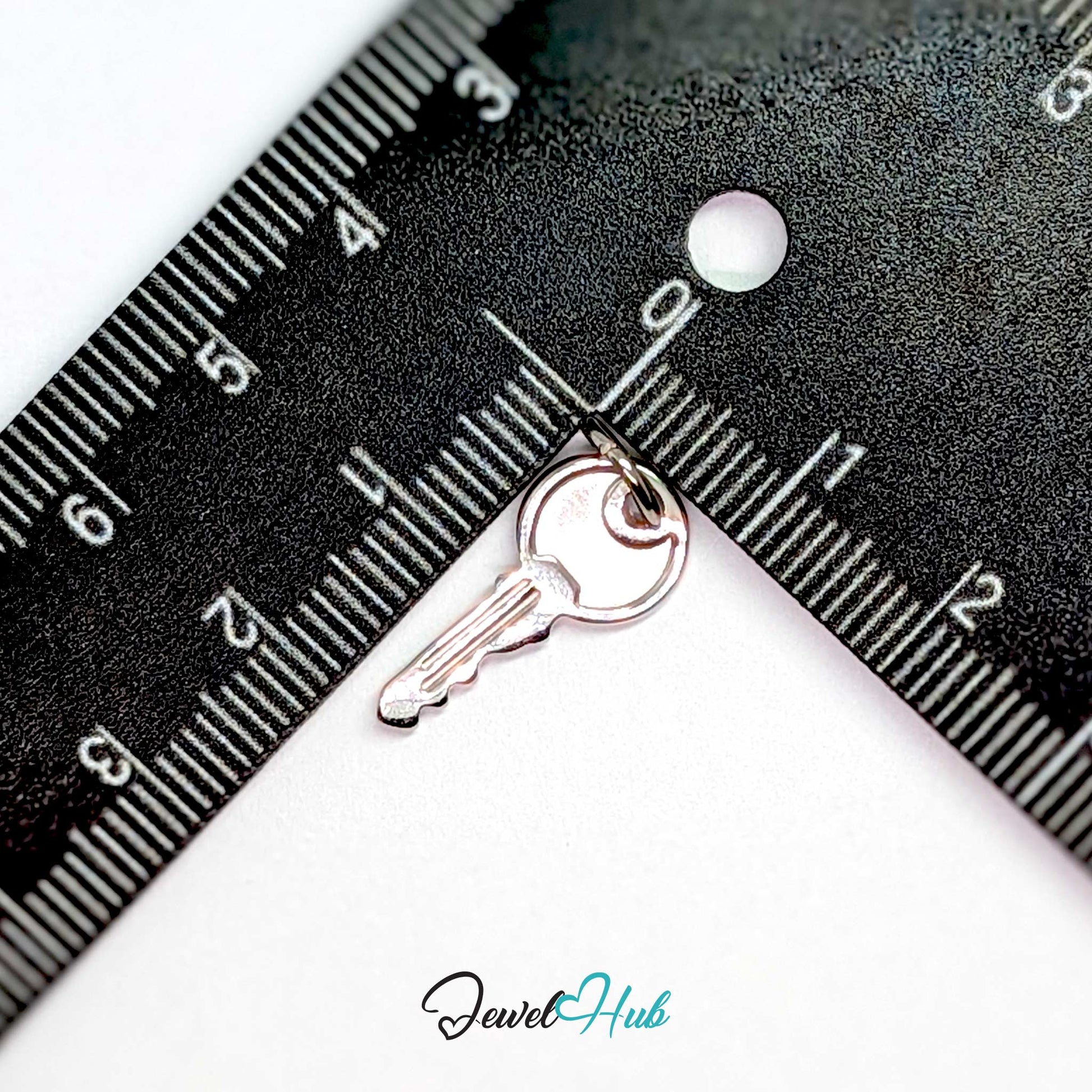 Everyday key charm in silver stainless steel with a plain round head - beside a ruler for scale - JewelHub