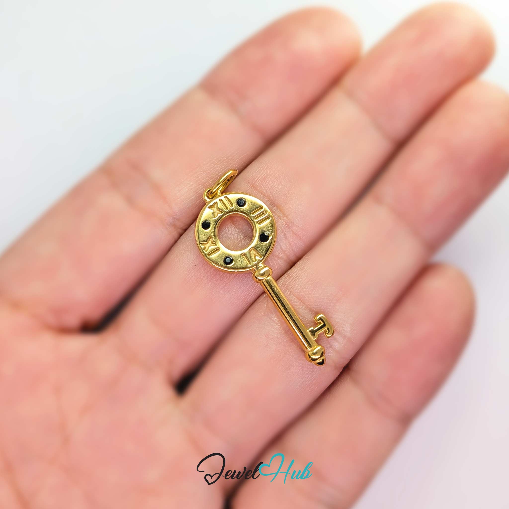 Roman numeral key charm in gold stainless steel with black stones - held in the hand for scale - JewelHub