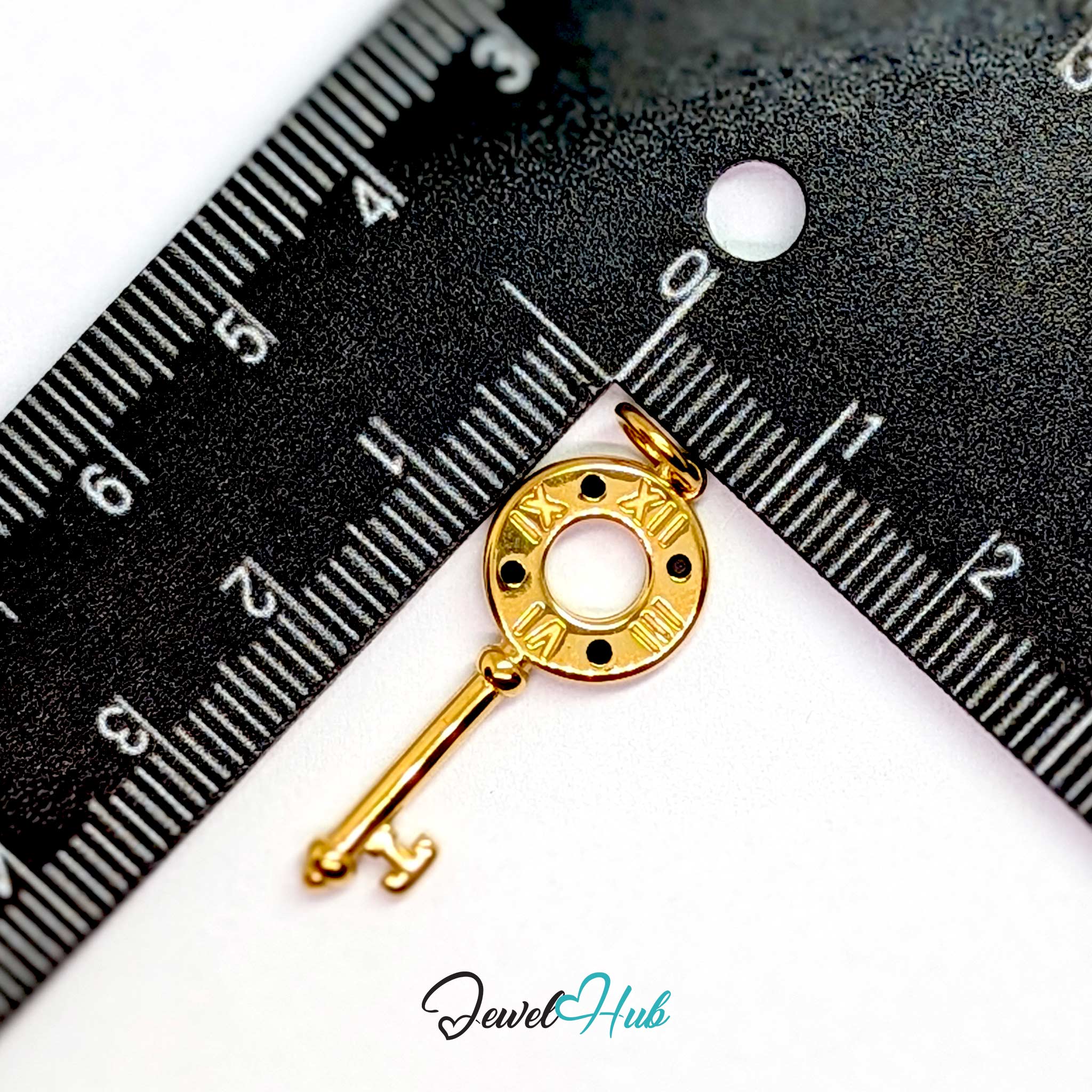 Roman numeral key charm in gold stainless steel with black stones - beside a ruler for scale - JewelHub