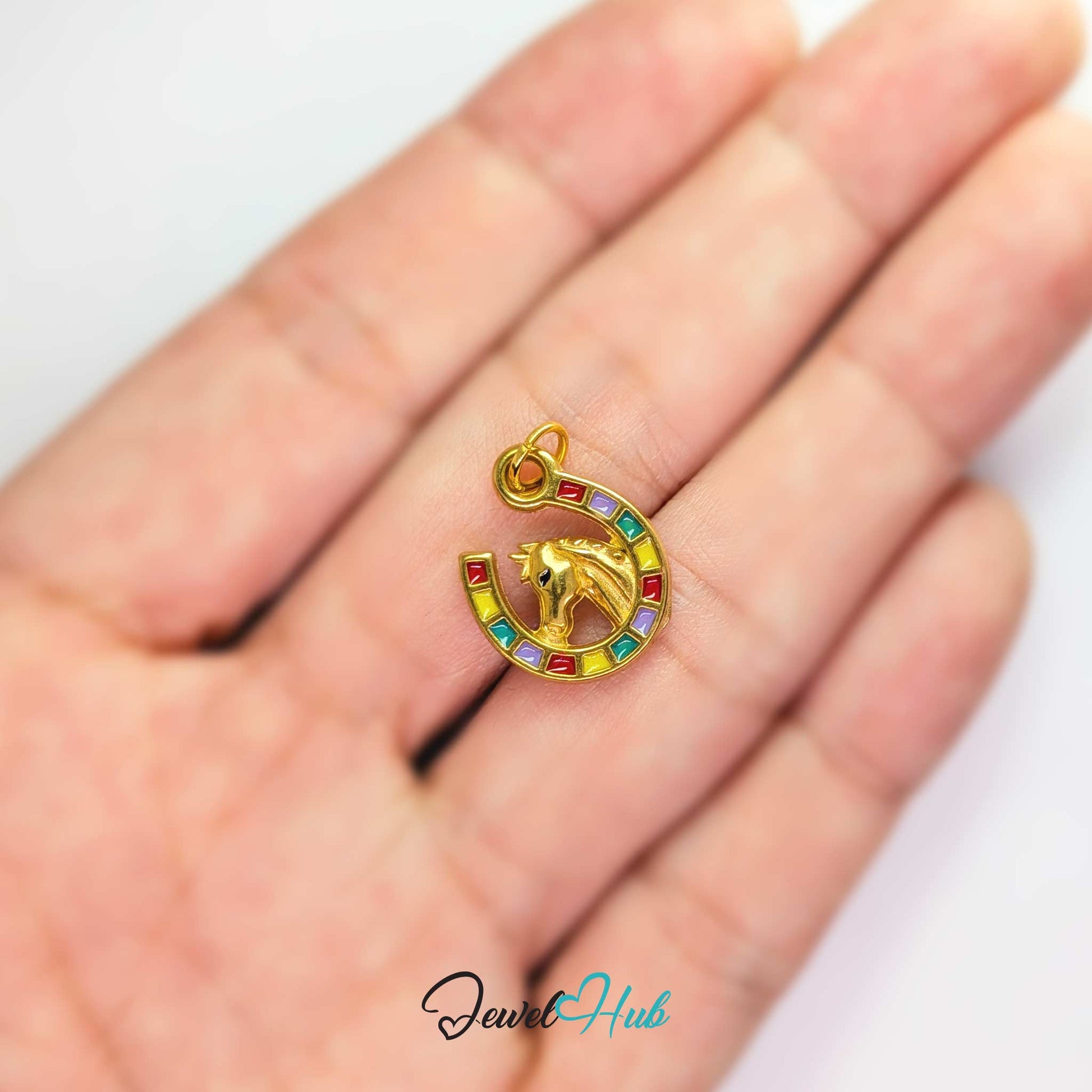 Mini key charm in gold stainless steel with four green stones - held in the hand for scale - JewelHub