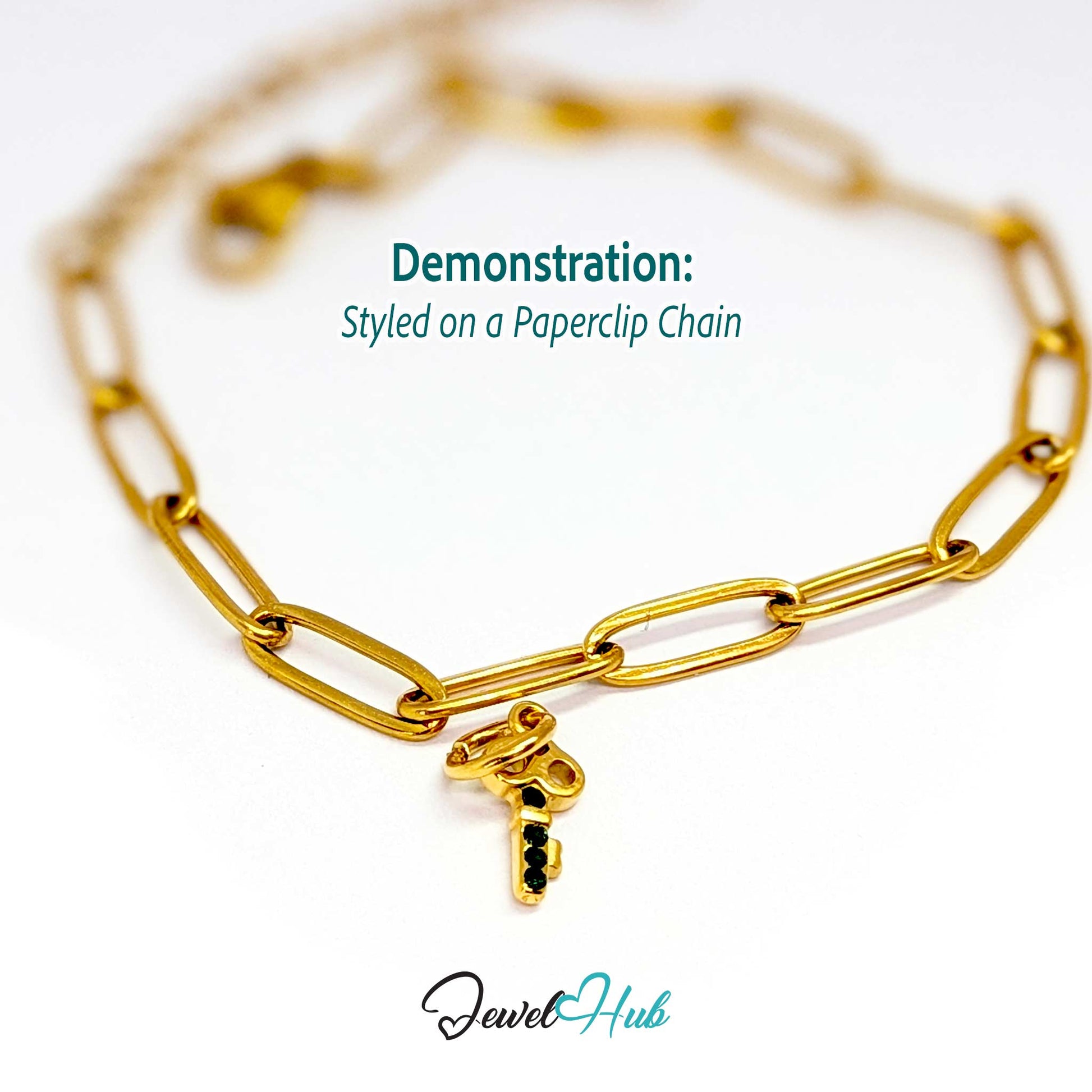 Mini key charm in gold stainless steel with four green stones - styled on a gold paperclip chain bracelet - JewelHub